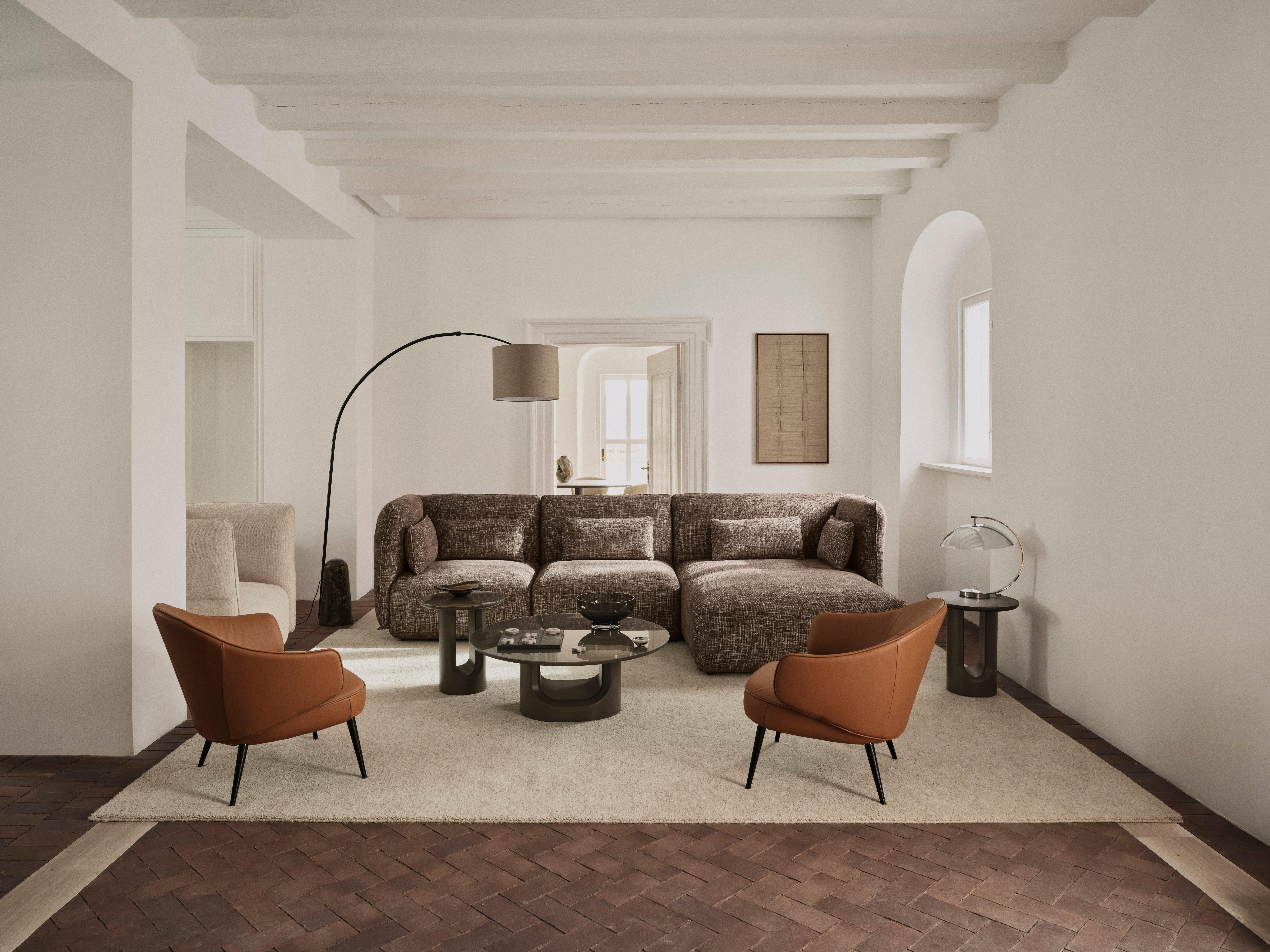 Modern living room with brown sectional sofa, two tan armchairs, round coffee tables and floor lamp.