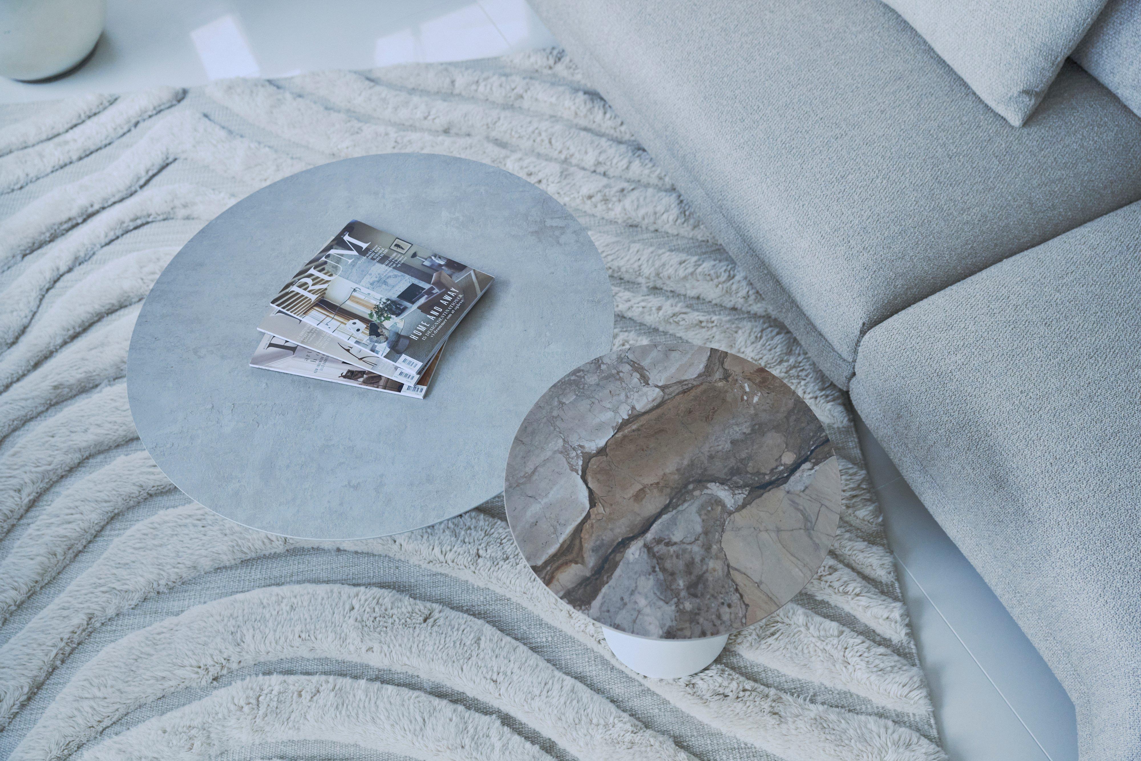 Two round coffee tables beside sofa, with magazines on the larger table.