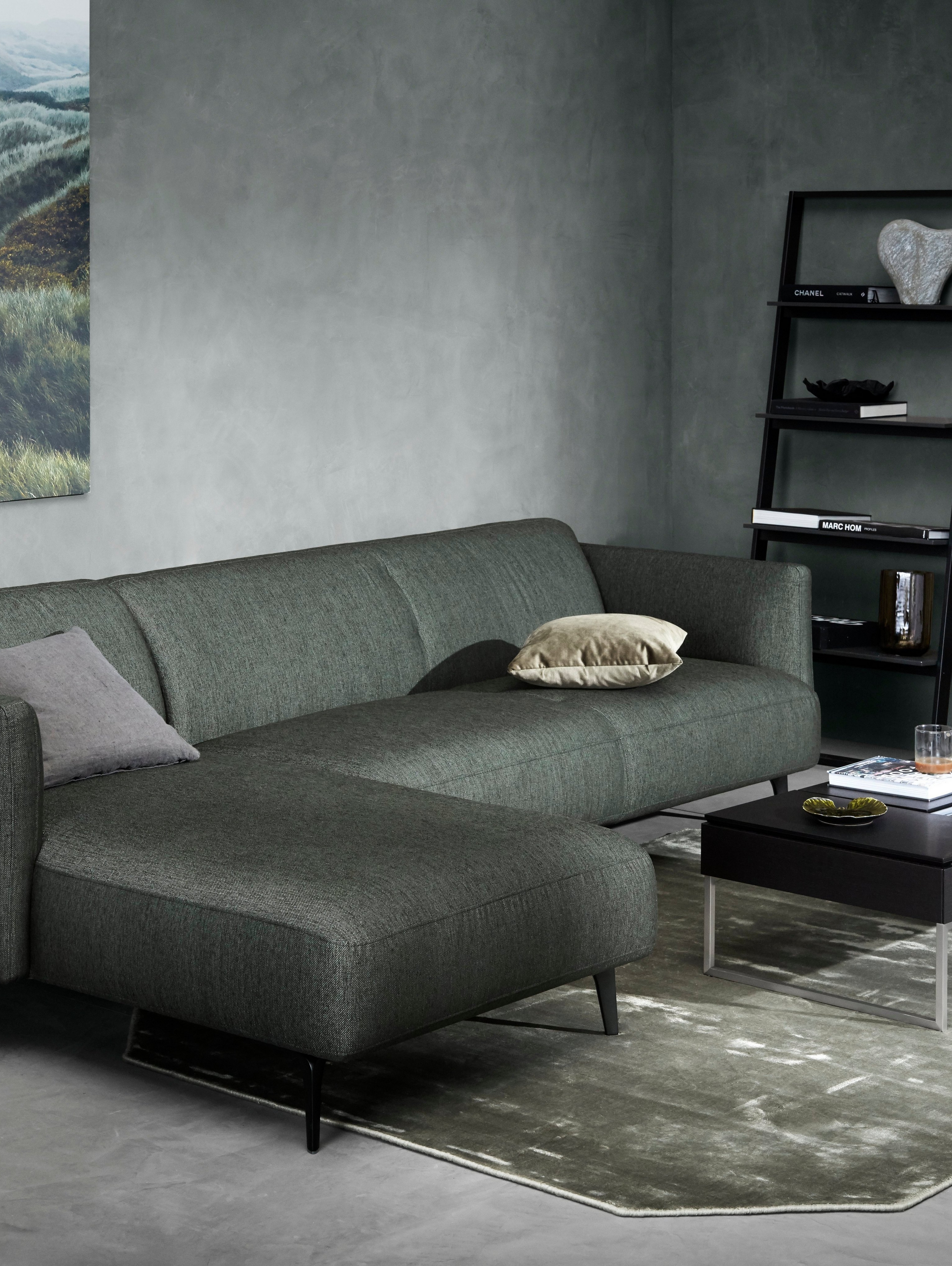 Modena sofa med hvilemodul i mørkegrønn Bristol tekstil i et dempet grønnmalt rom.