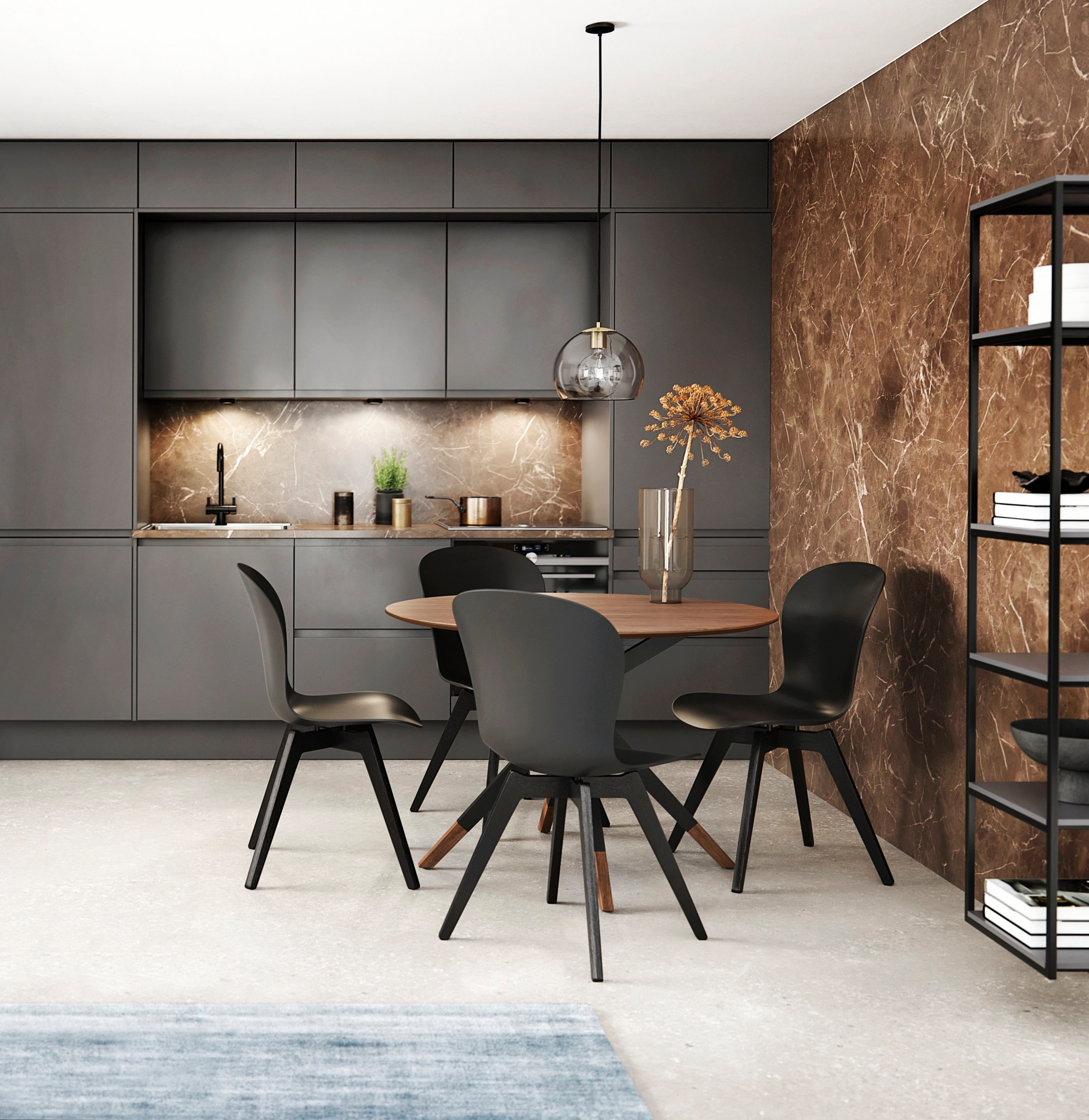 Moderne kjøkken med mørke skap, veggplate i marmor og spiseområde med rundt bord og svarte stoler.