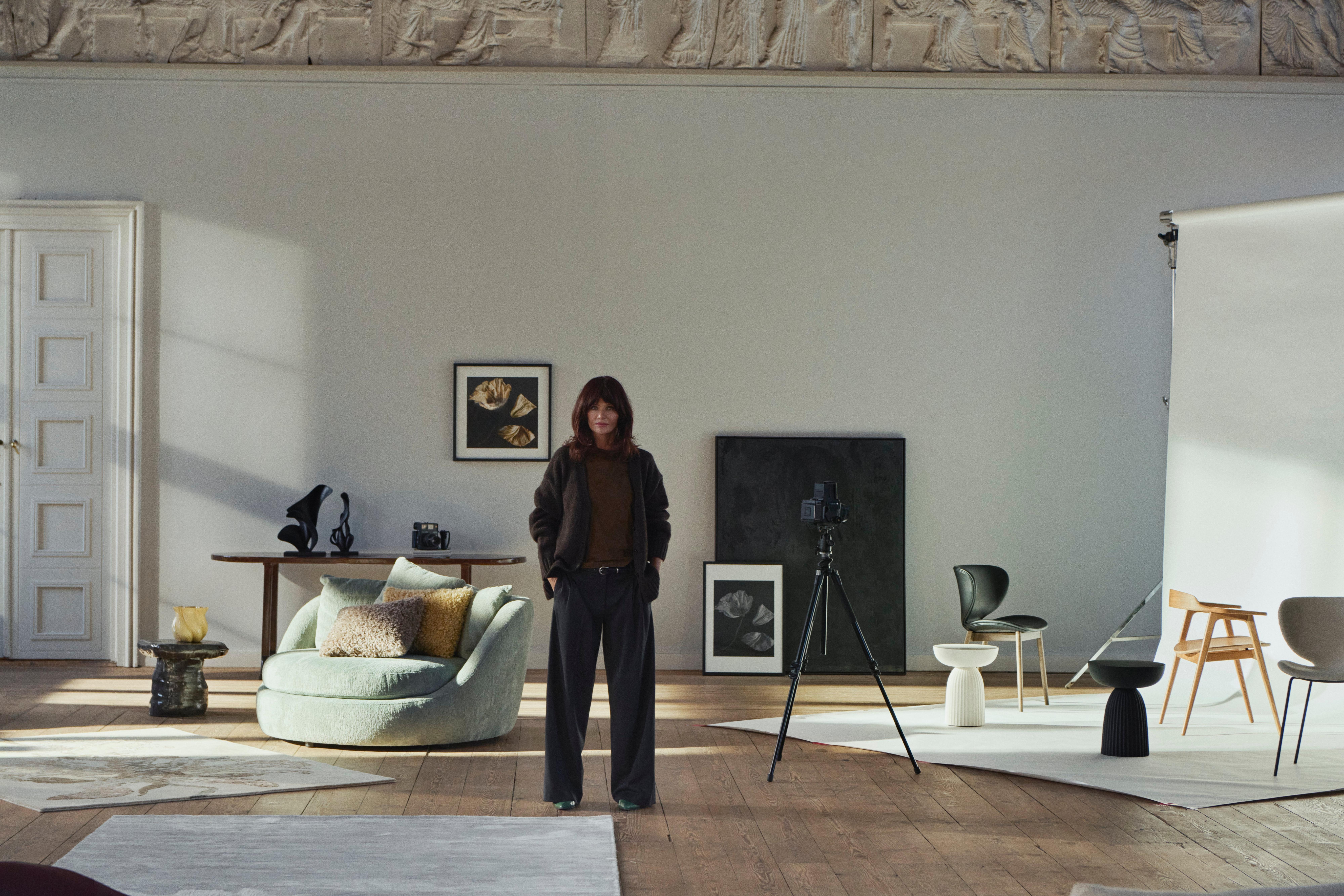 Espacio amplio con silla lounge verde, cojines Teddy, obras de arte y esculturas Flora y Helena Christensen de pie en el centro con equipo de estudio.