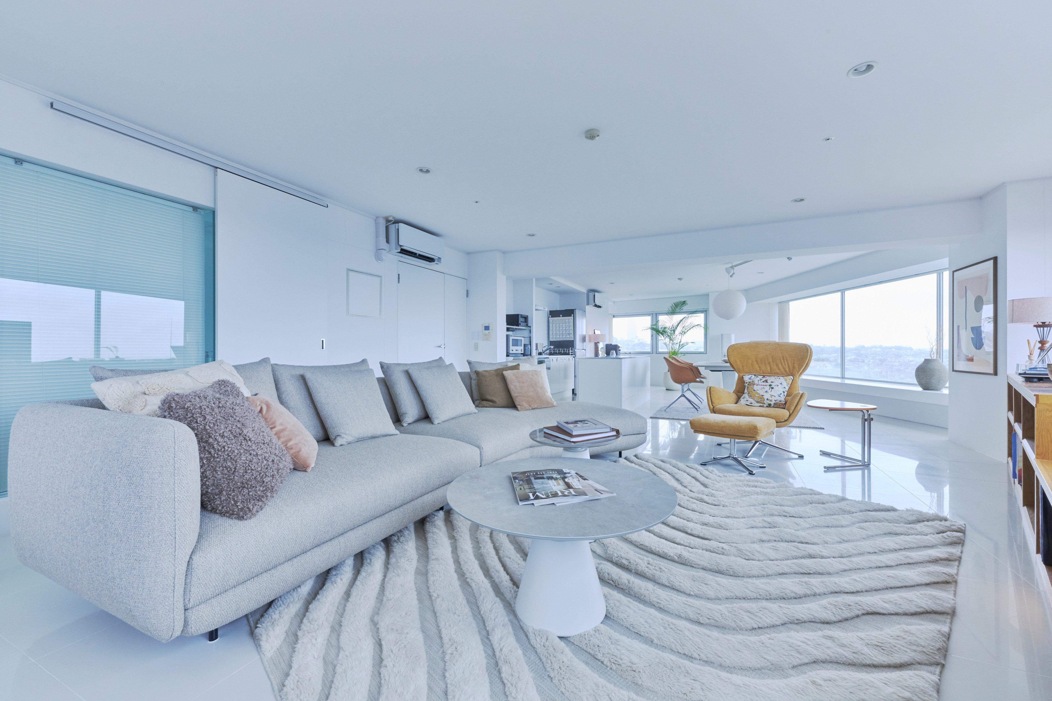 Light grey sofa with cushions, round coffee table and mustard armchair in modern living room.