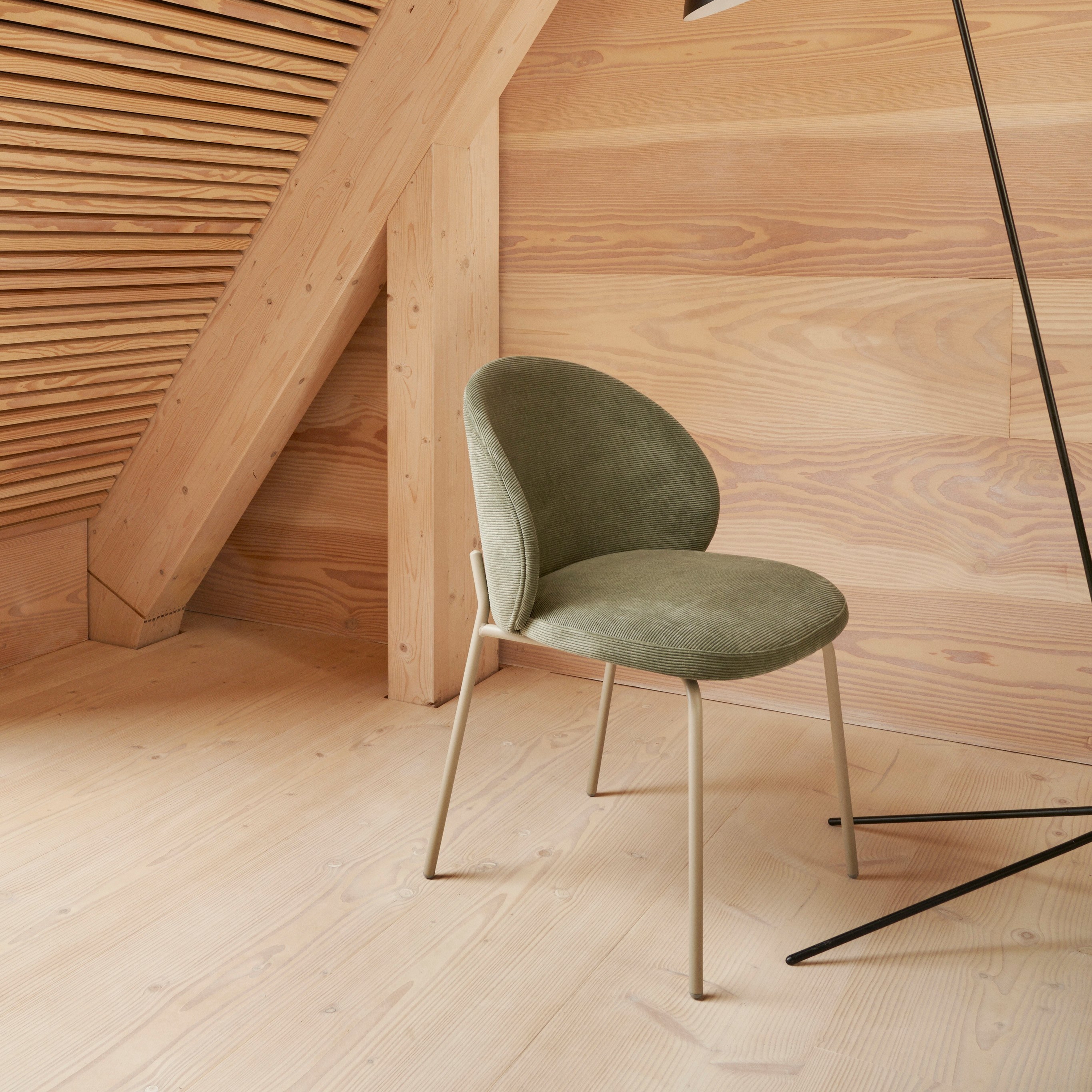 角落中的 Princeton 椅子採用綠色 Bresso 布料襯墊，搭配 Demand 落地燈。