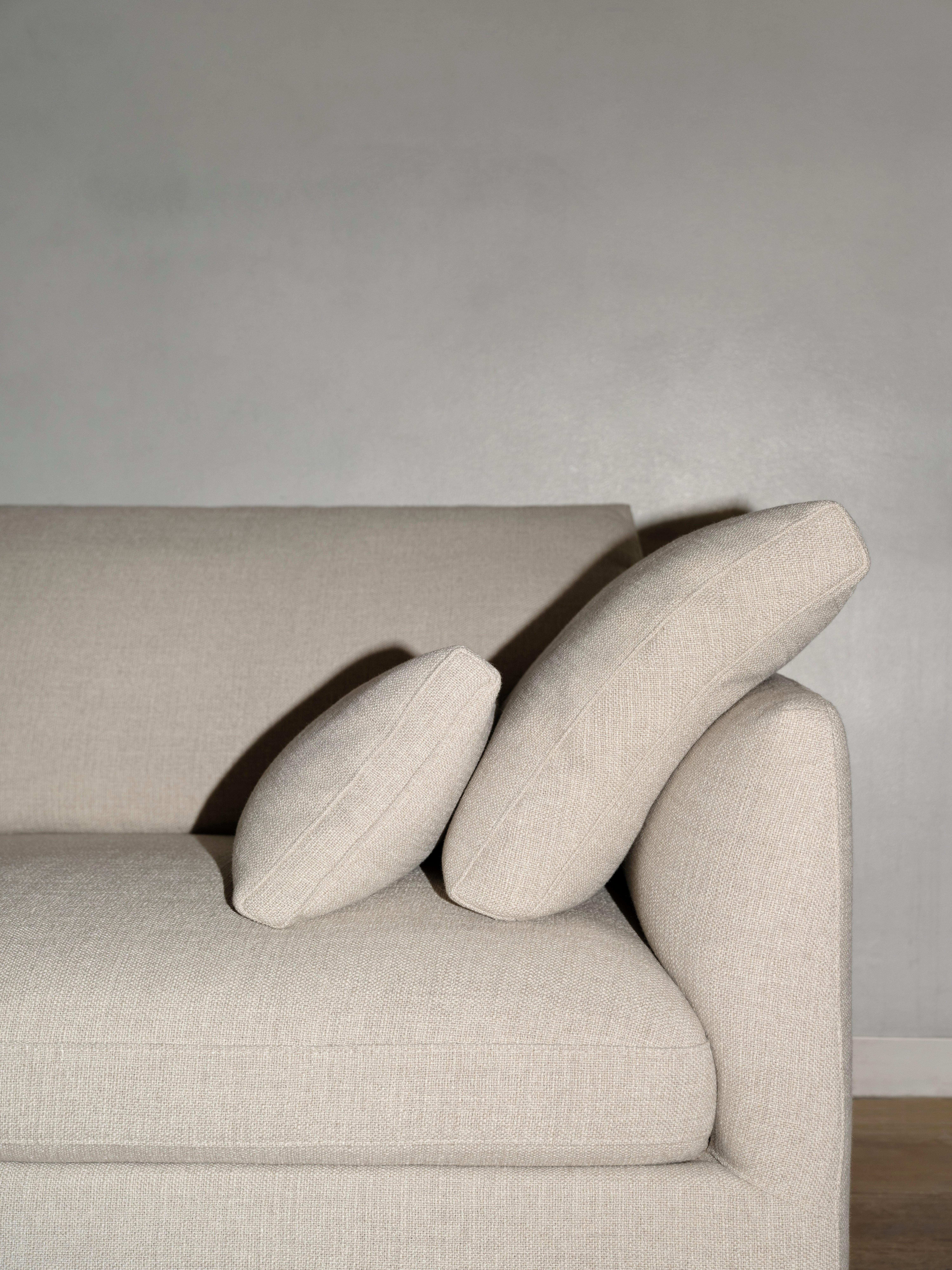 Milano side table in brown marble with yellow decor object beside Milano corner sofa in beige Arezzo fabric, on wooden floor.