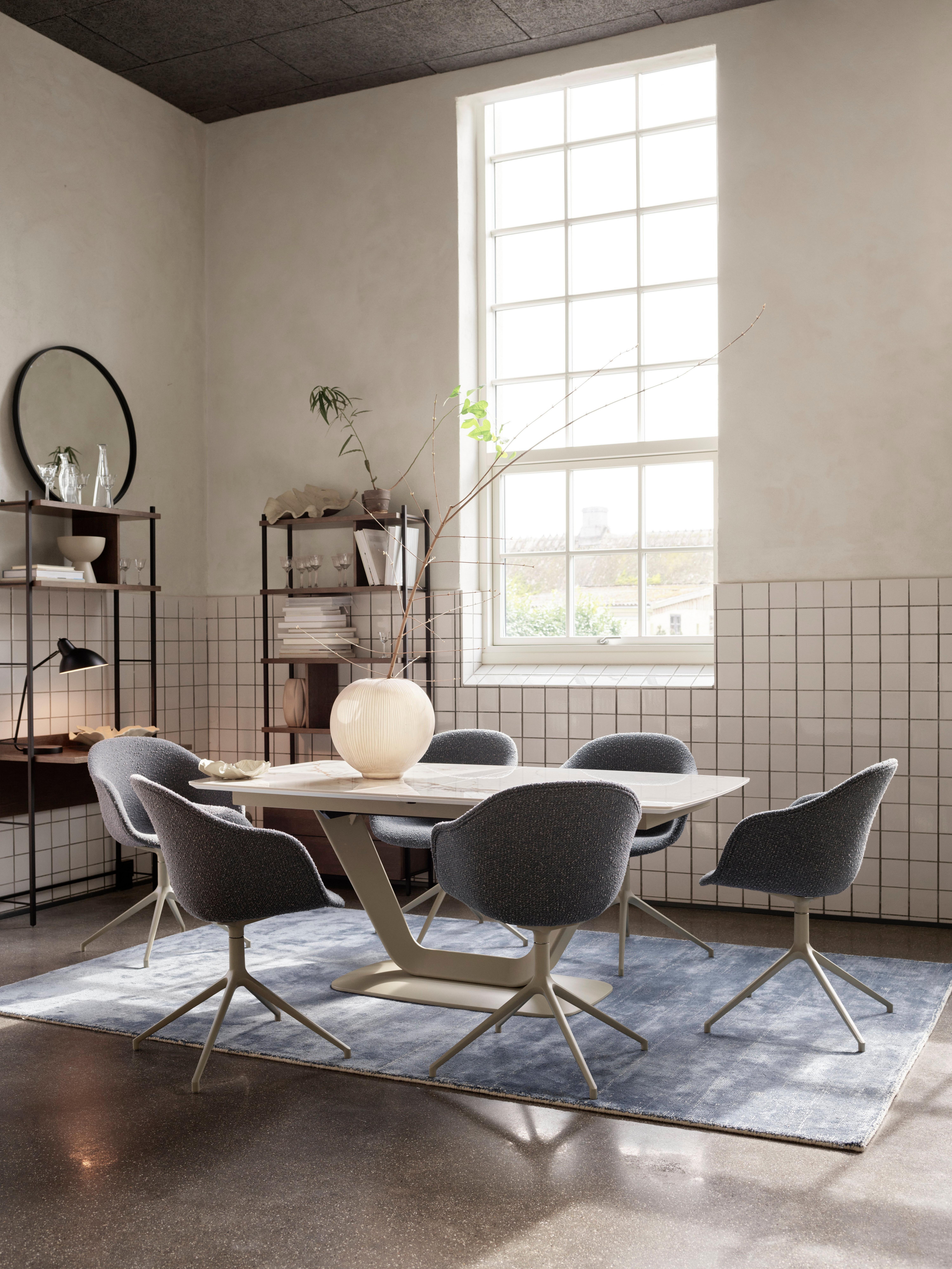 Modern dining room with a rectangular table, six blue Adelaide chairs, a ceramic vase centerpiece, a blue Simple rug, and large window.