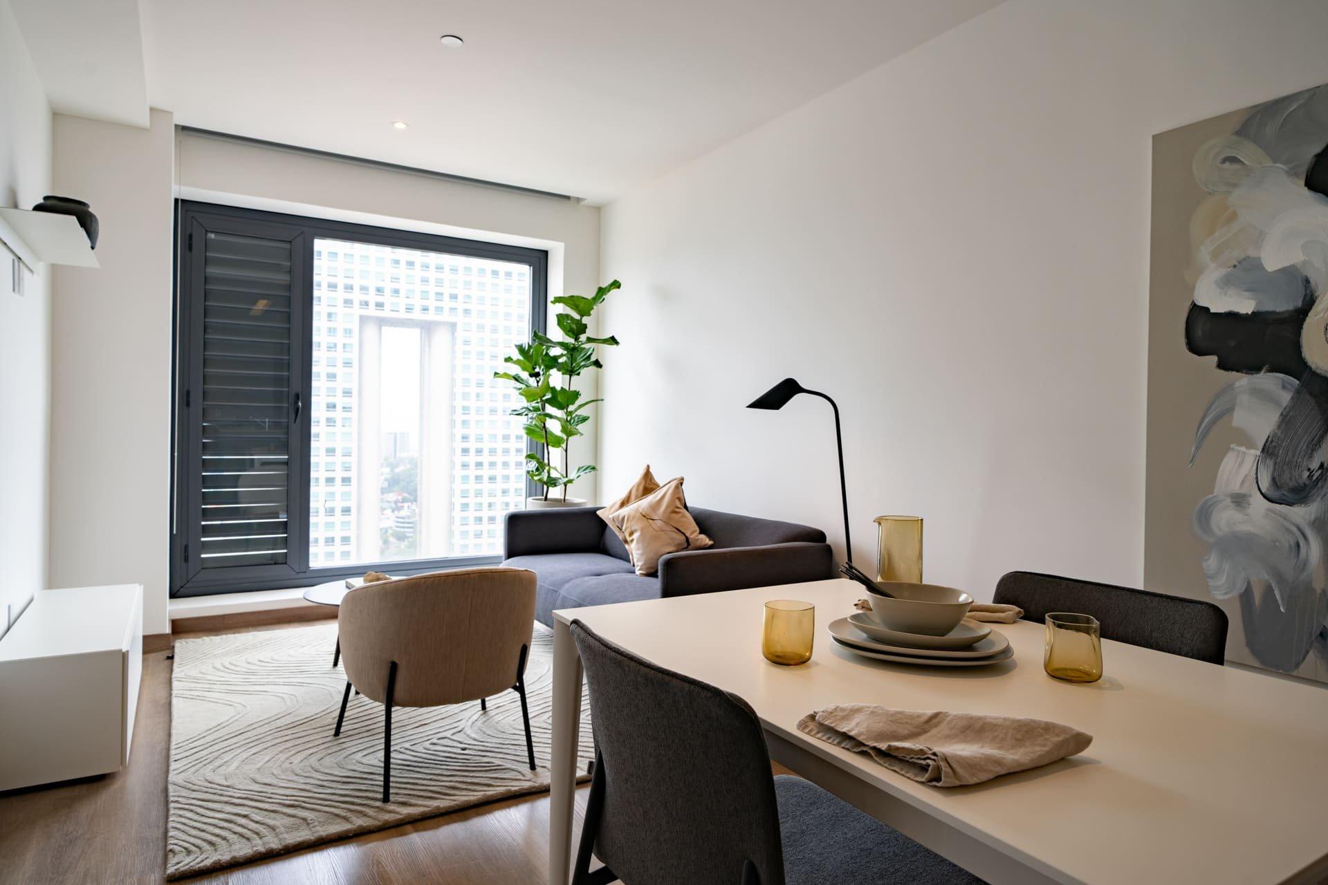 Modern dining area with art, adjacent to kitchen and view into hallway, natural decor elements.
