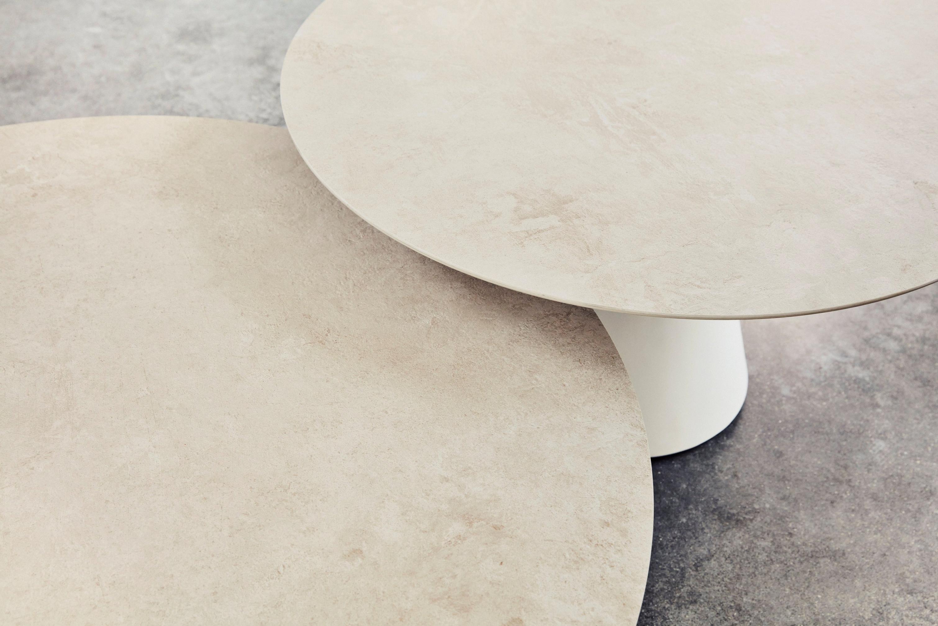 Two overlapping round ceramic Madrid tabletops with neutral tones