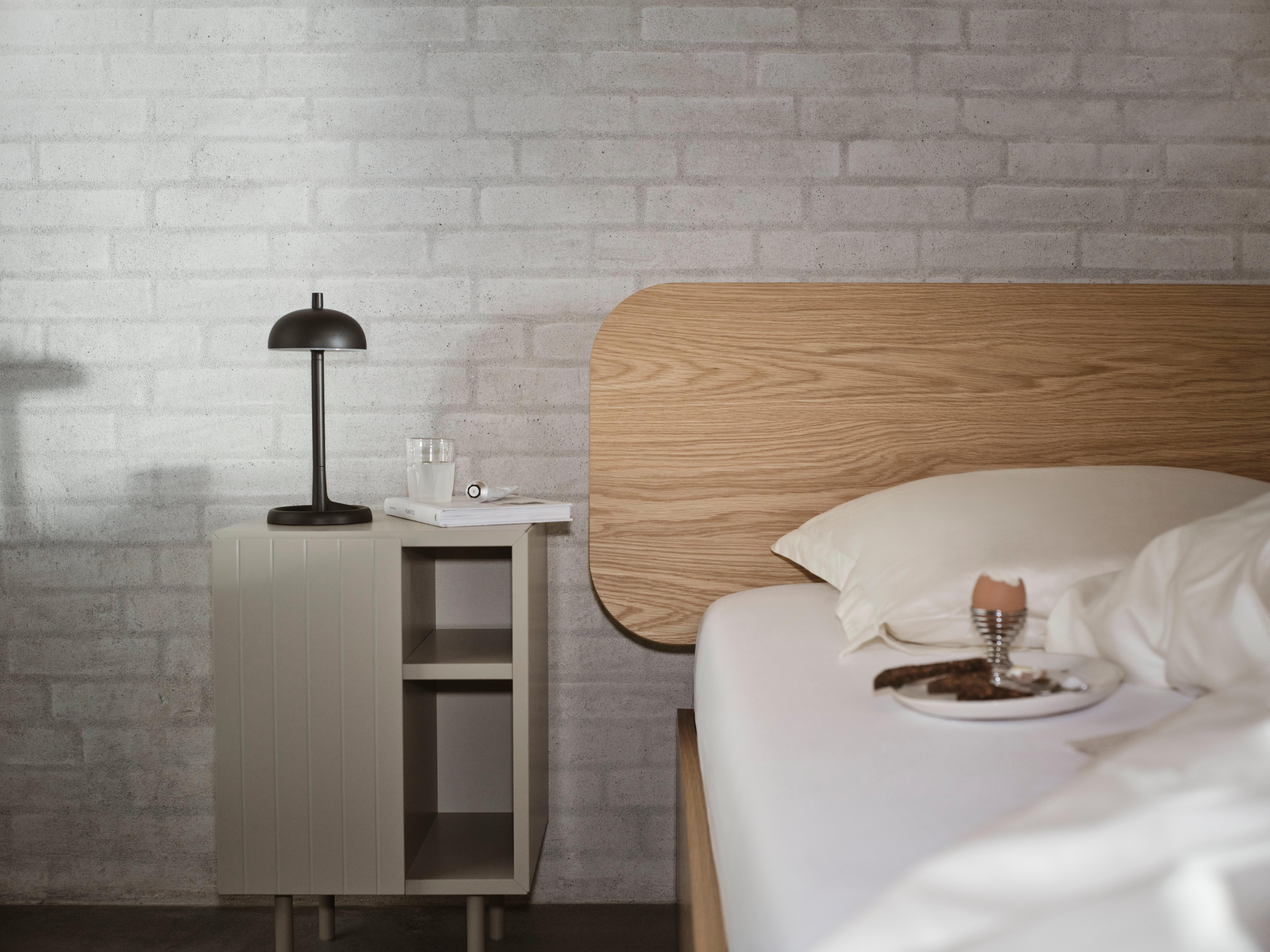 Element 床搭配弧形木質床頭板，旁側為採用霧面灰色漆面處理的 Lugano 床頭櫃。