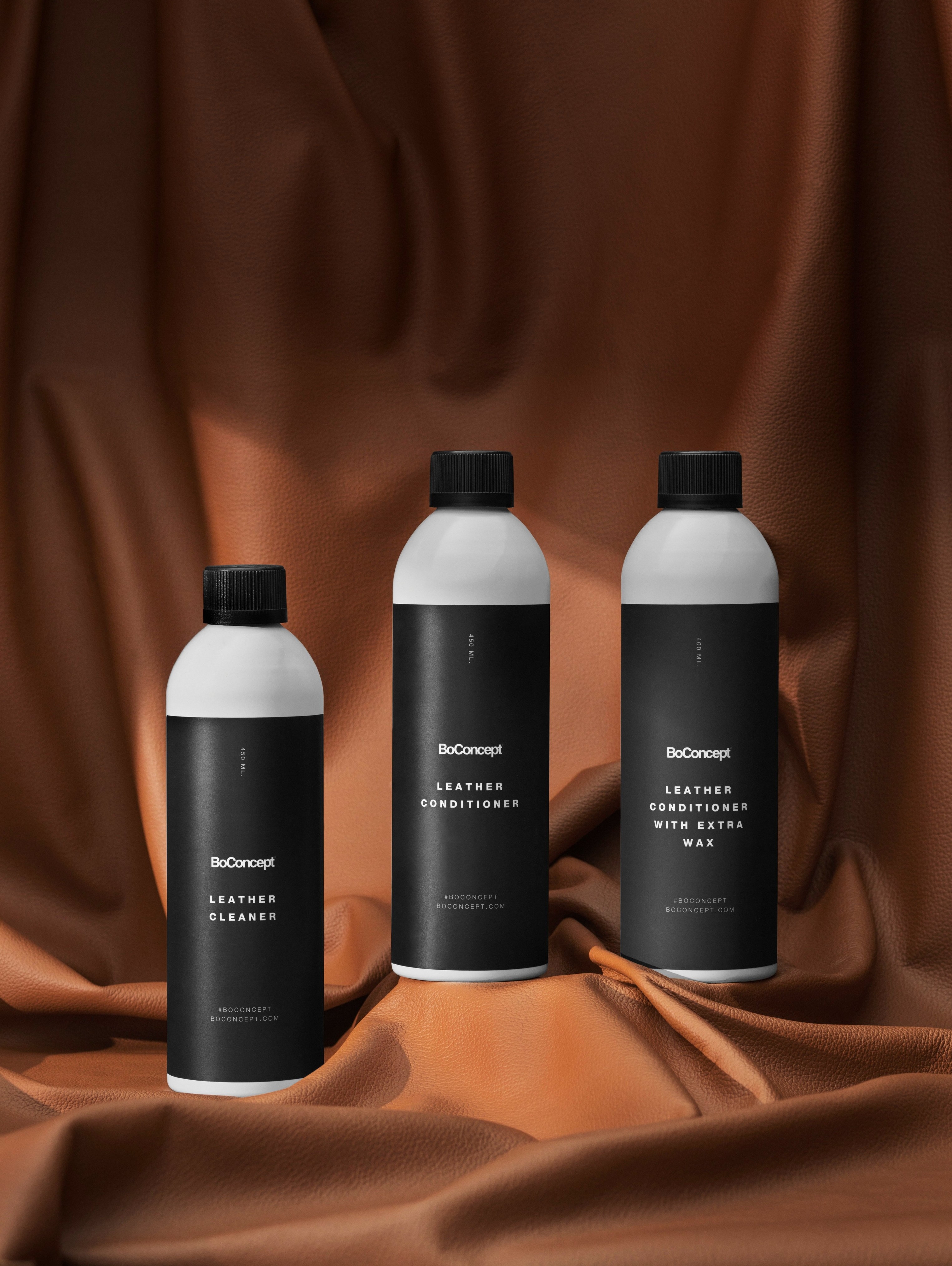 Tri produkty BoConcept na starostlivosť o kožu na nariasenej koži karamelovej farby.