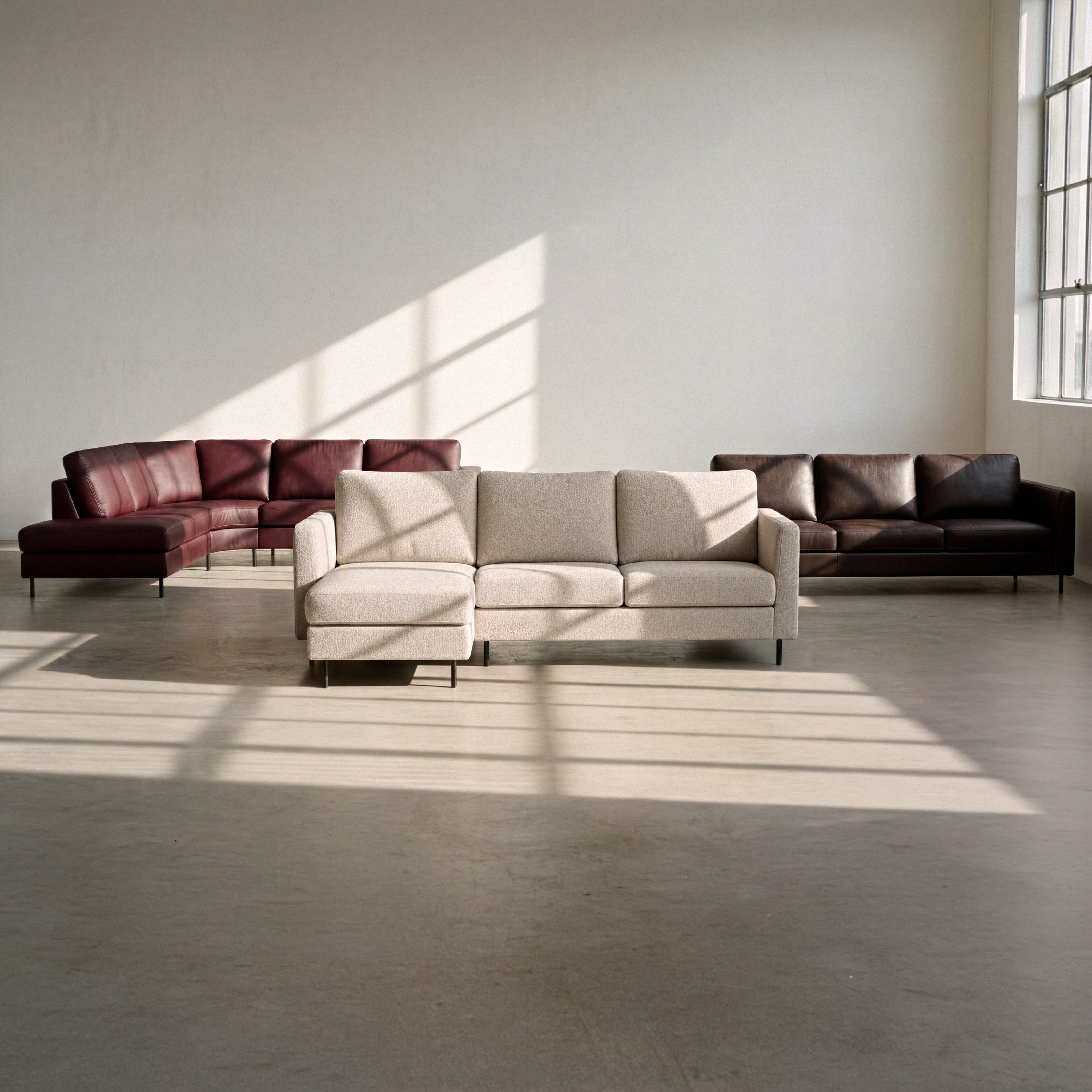 Sofá chaise longue beige con patas negras, junto a sofás de cuero burdeos y marrón.