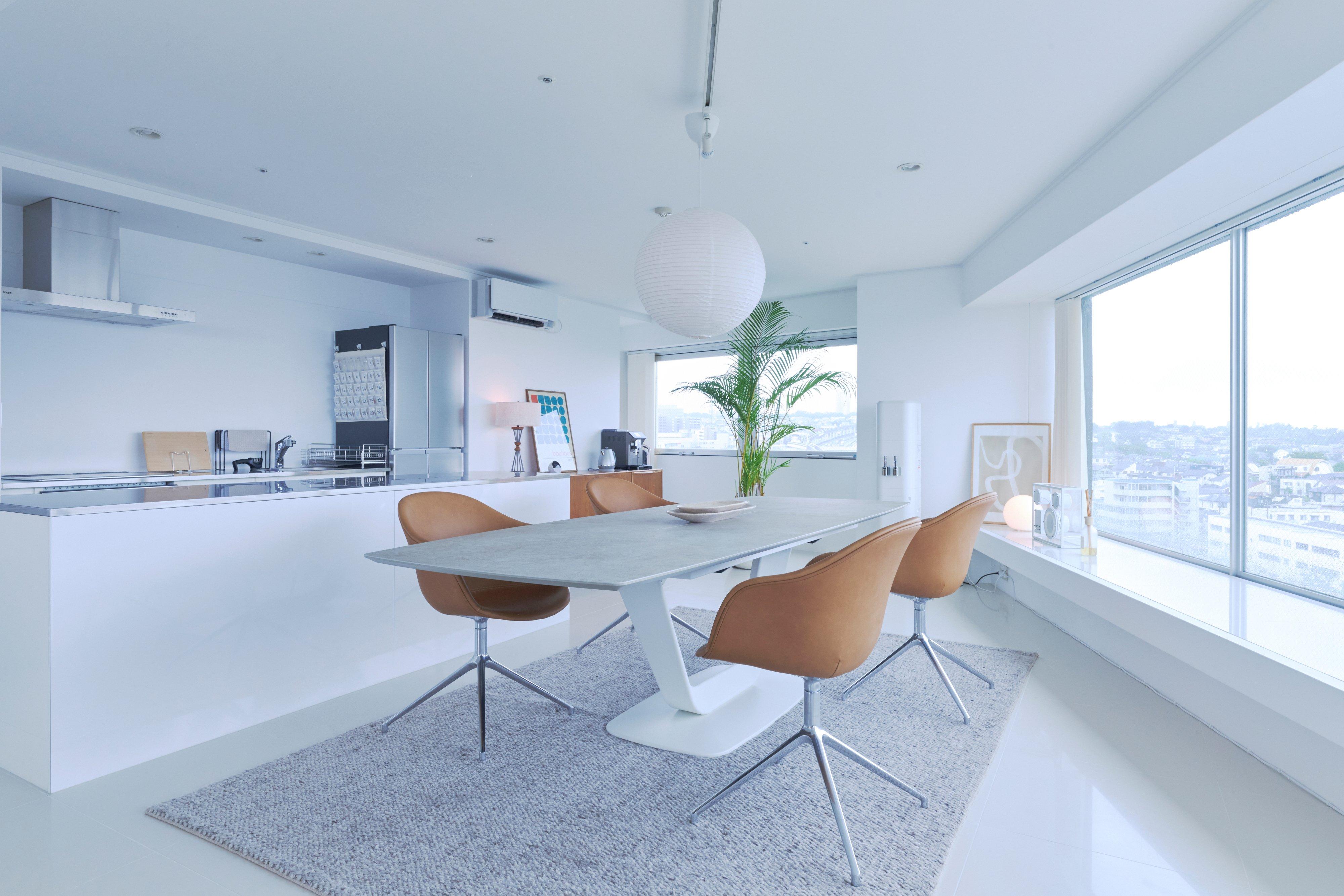 Modern dining table with four tan swivel chairs in an open-plan kitchen.