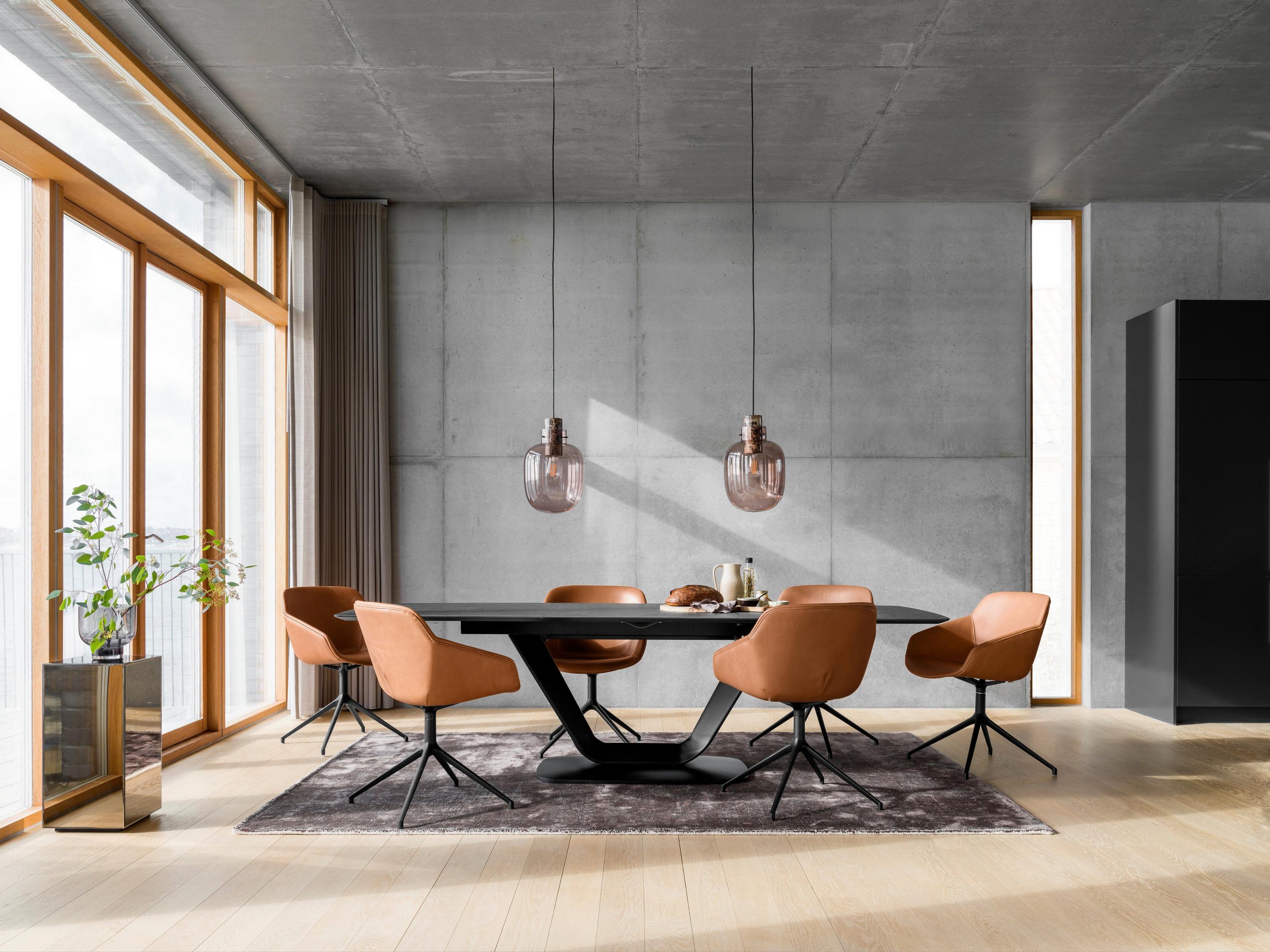 Modern dining room with tan chairs, a black table, pendant lights, and large windows with a city view.