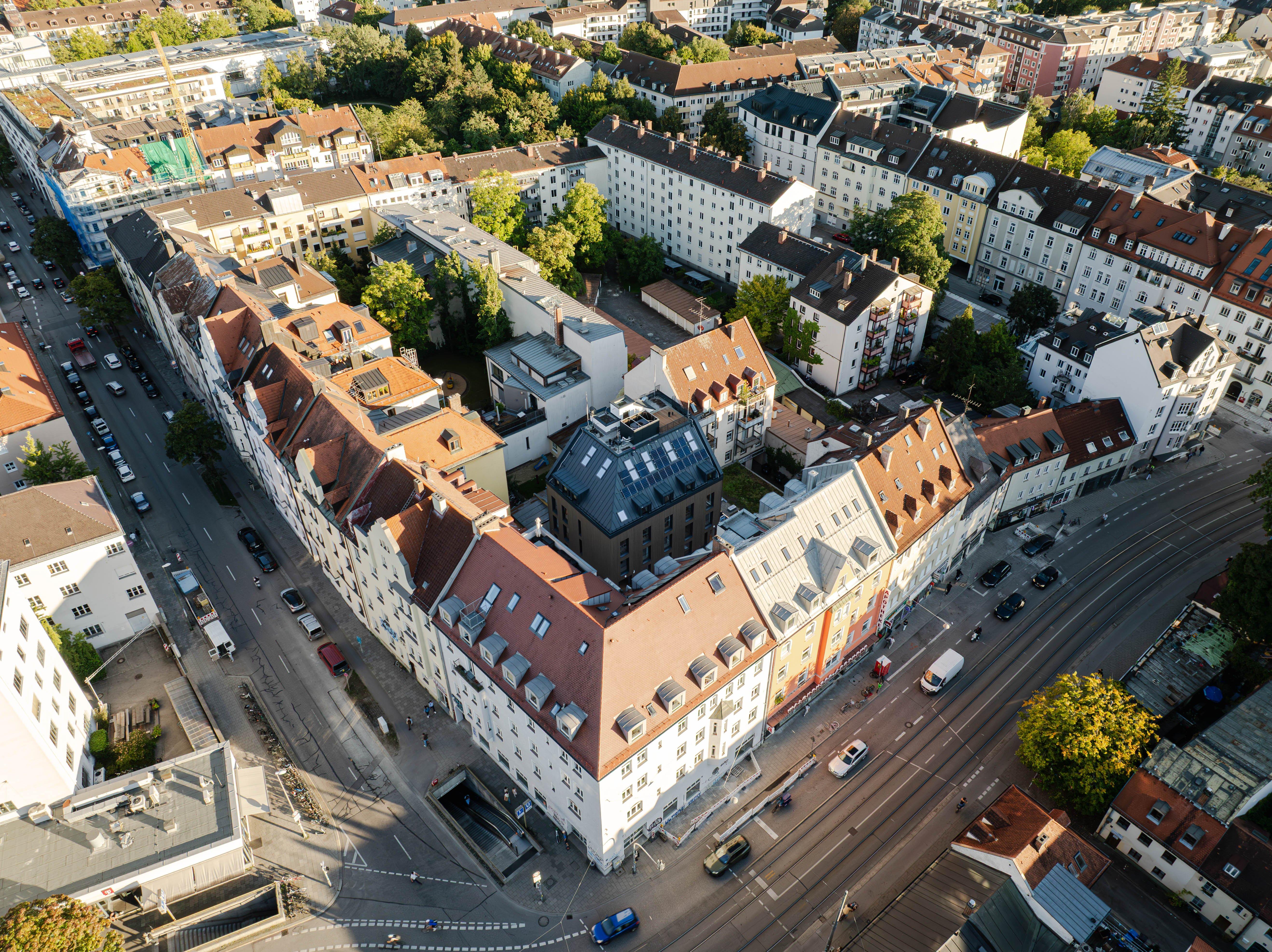 Vue aérienne d'un quartier urbain avec immeubles aux toits rouges et rues animées.