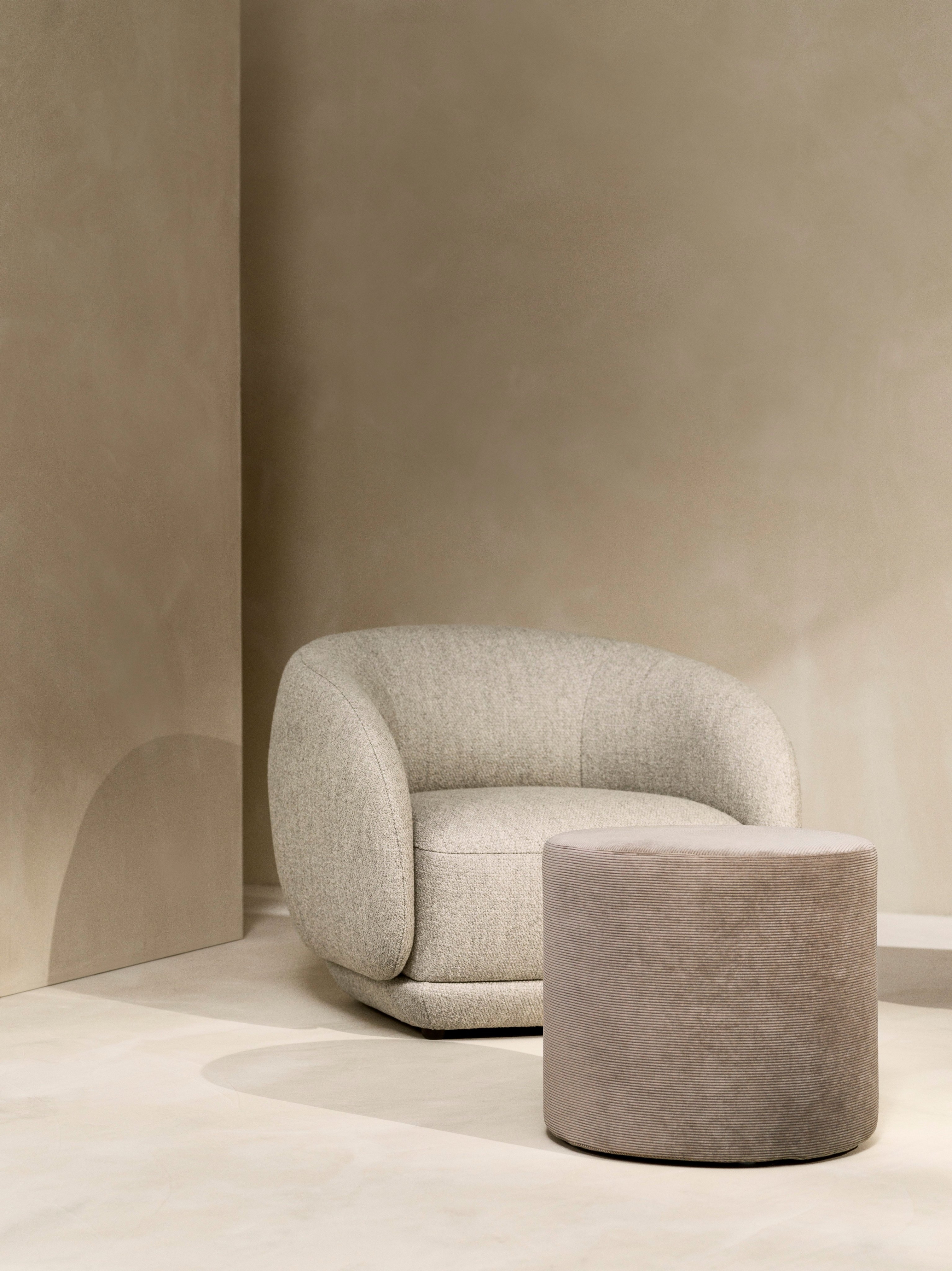 Quiet corner with the Bolzano armchair in beige Lazio fabric and the Eden footstool in sand Skagen fabric.