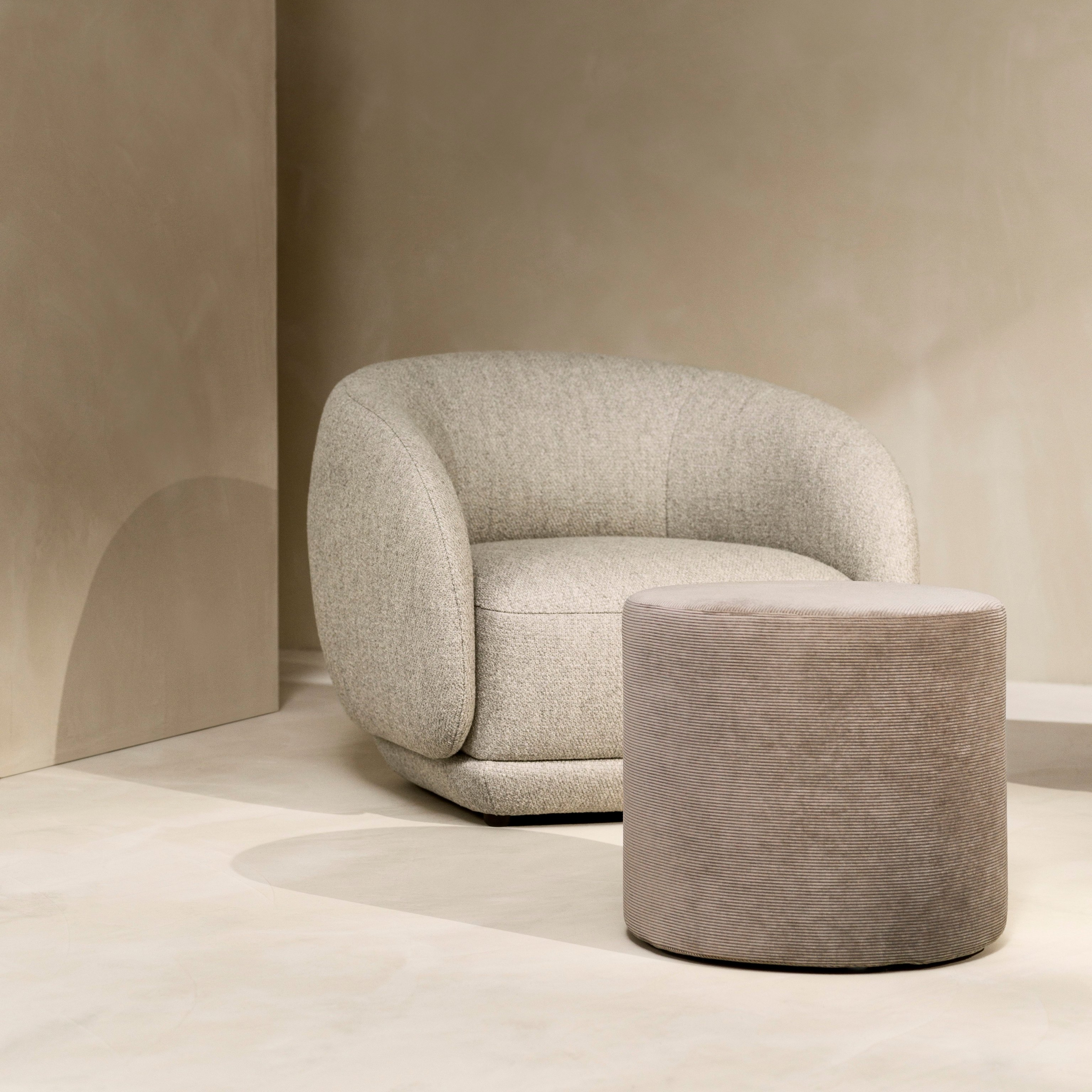 Rustige hoek met de Bolzano fauteuil in beige Lazio stof en de Eden voetenbank in zandkleurige Skagen stof.