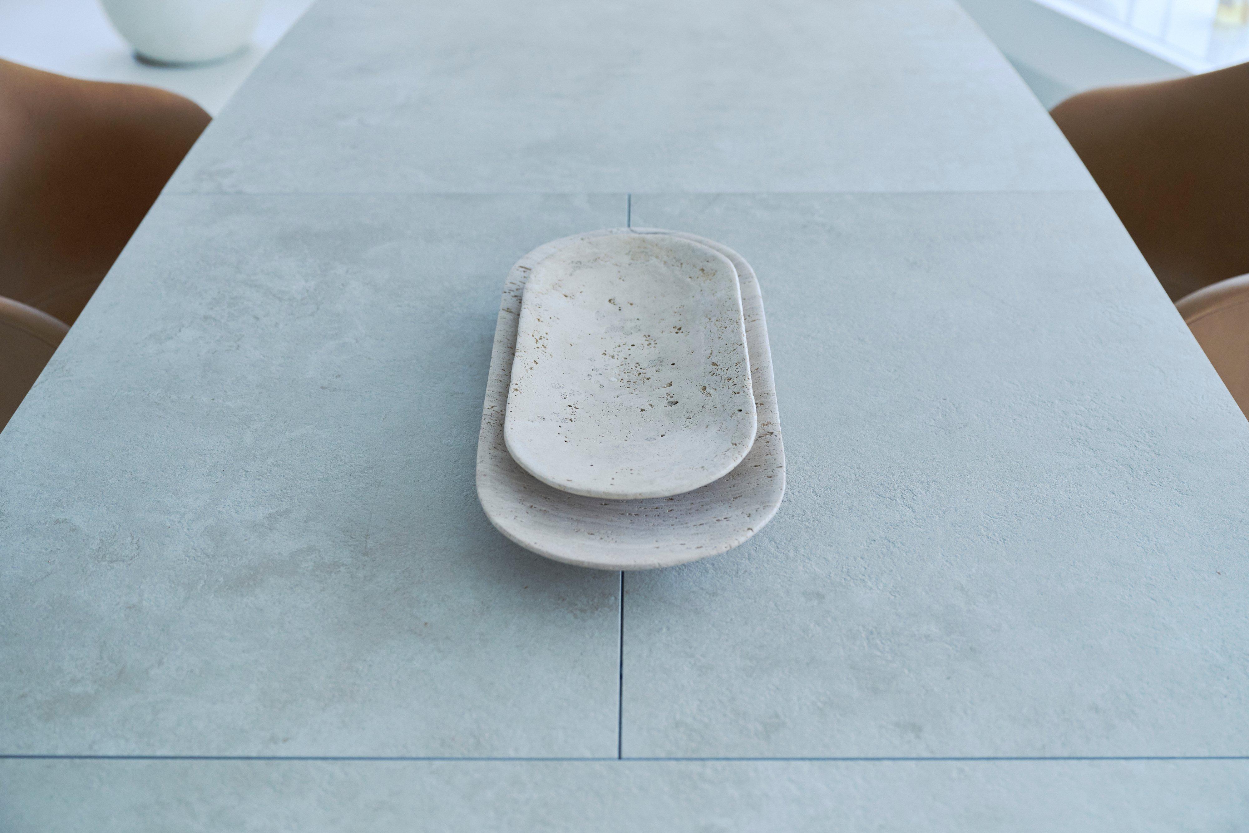 Two stacked speckled white serving platters on a table.
