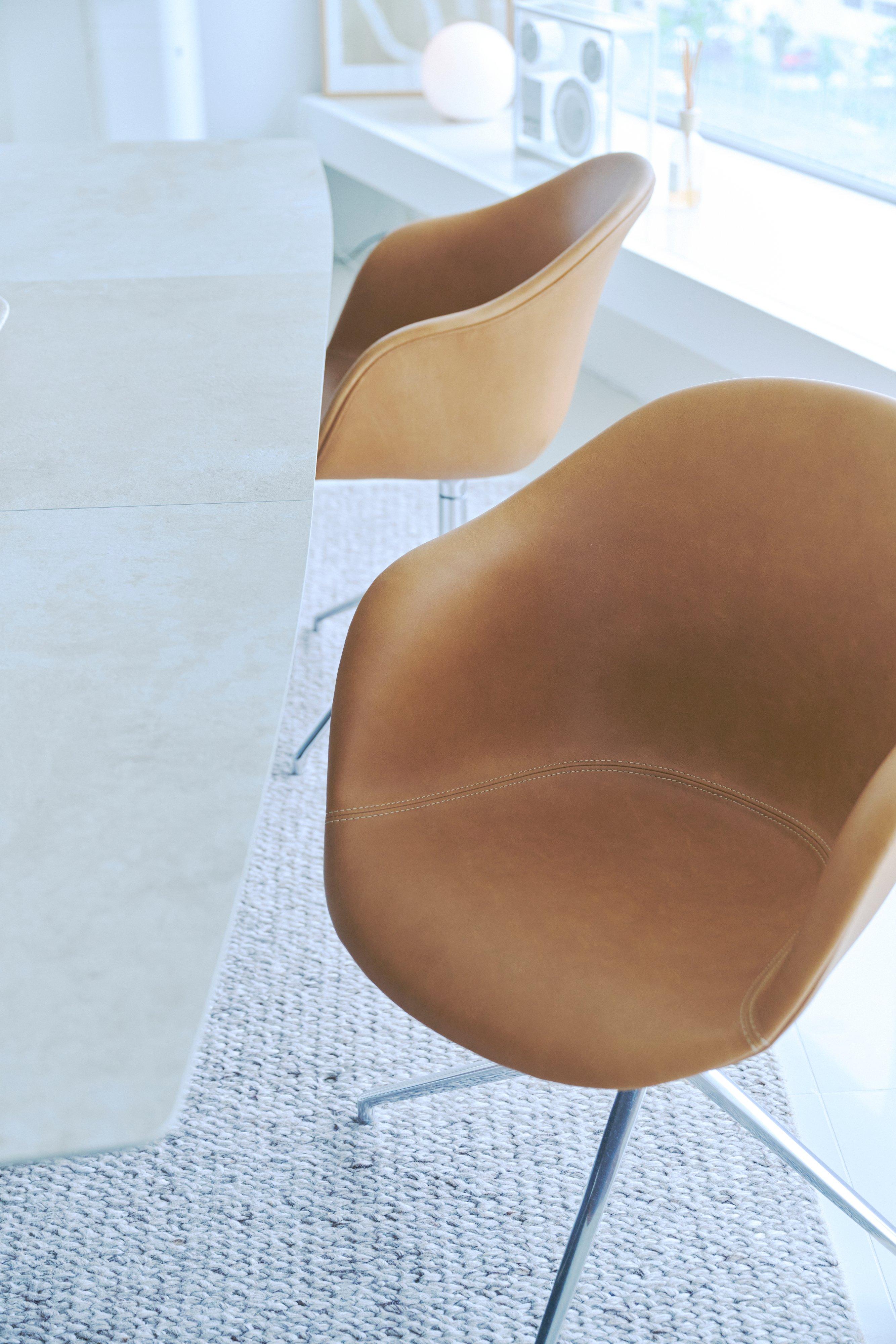Tan upholstered dining chairs with metal legs beside a light table.