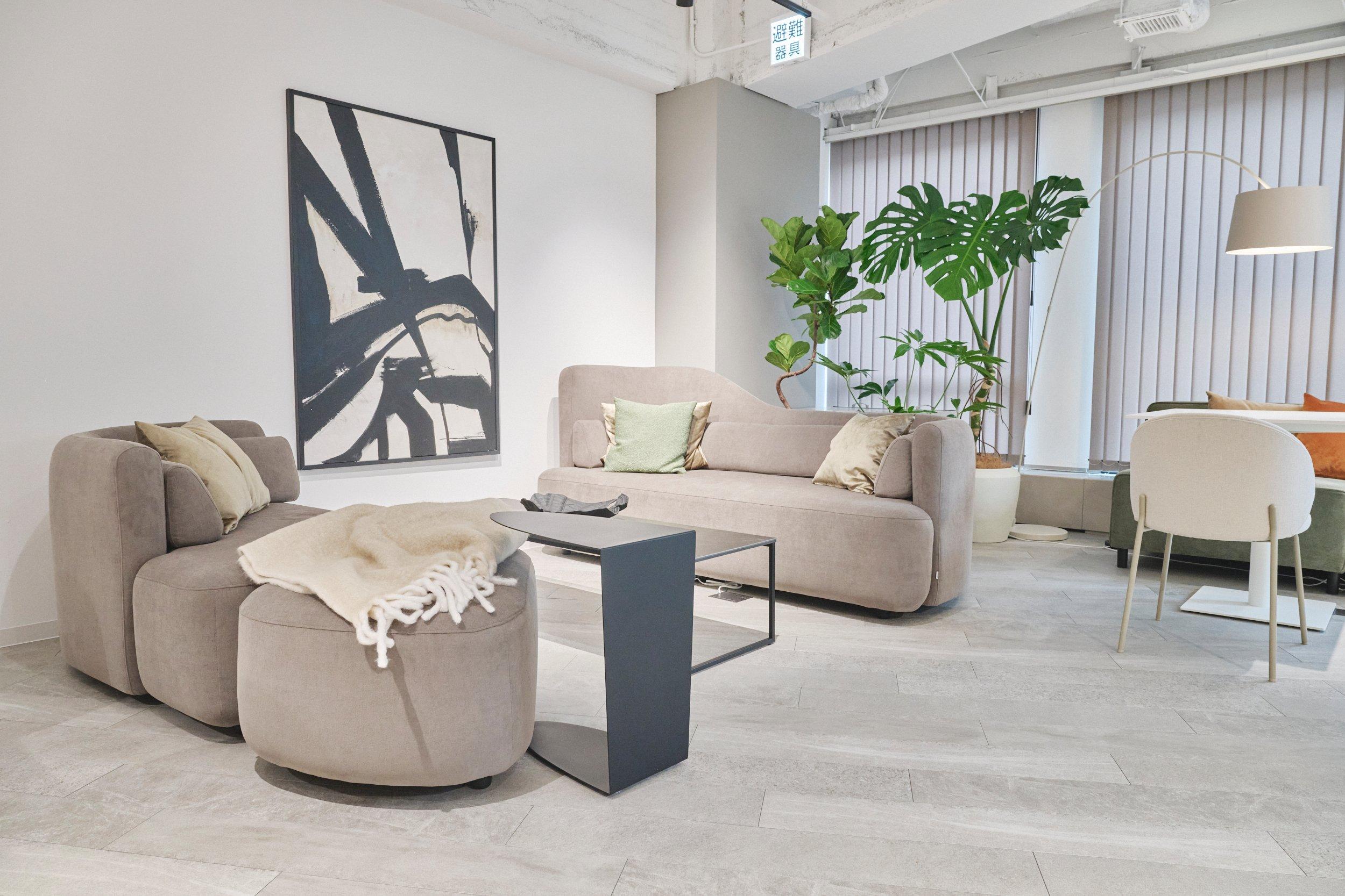 Sala moderna con sofás grises, plantas y arte abstracto en la pared.