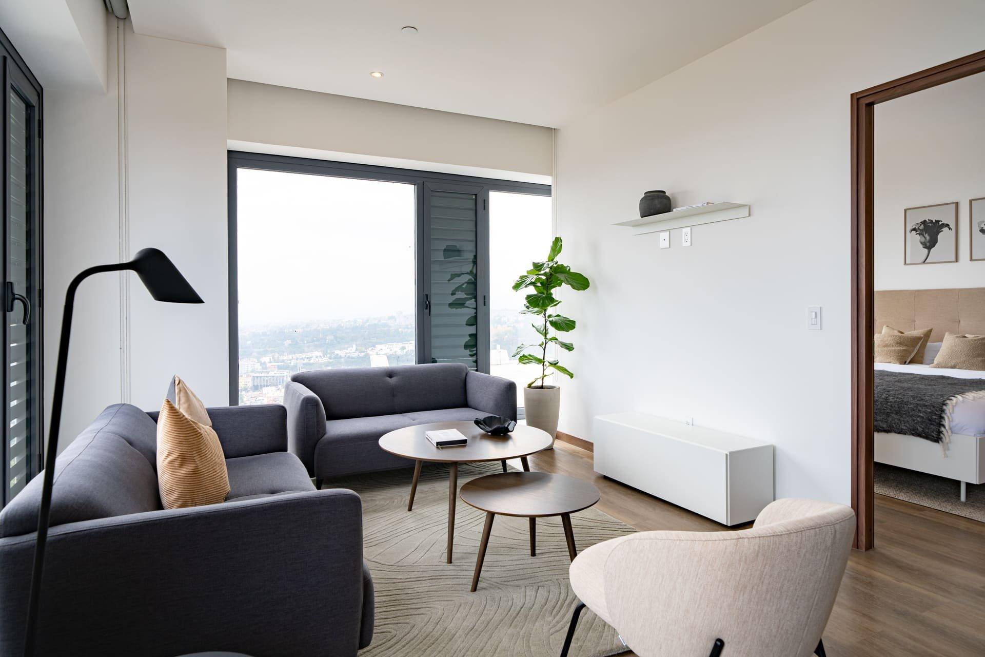 Contemporary living room with sofa set, cityscape view, and bedroom in the background.