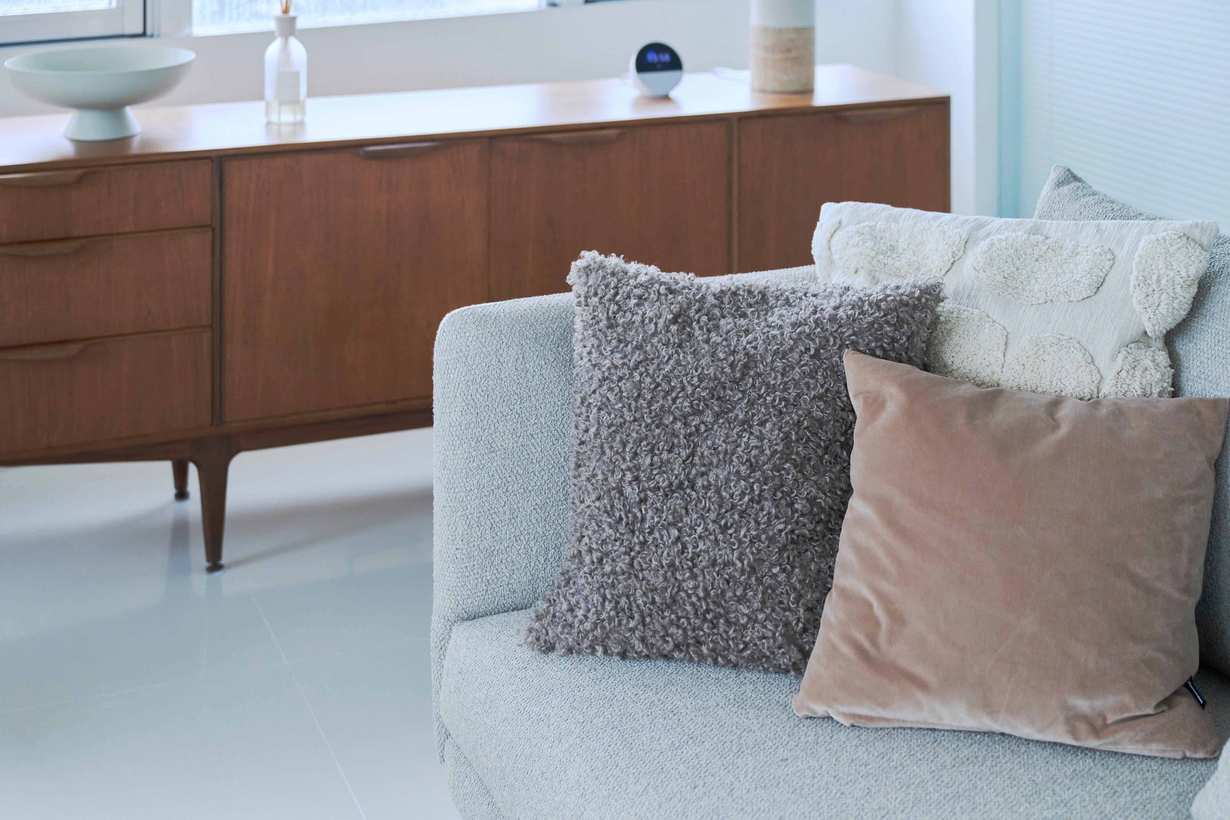 Three textured throw cushions on a light sofa.