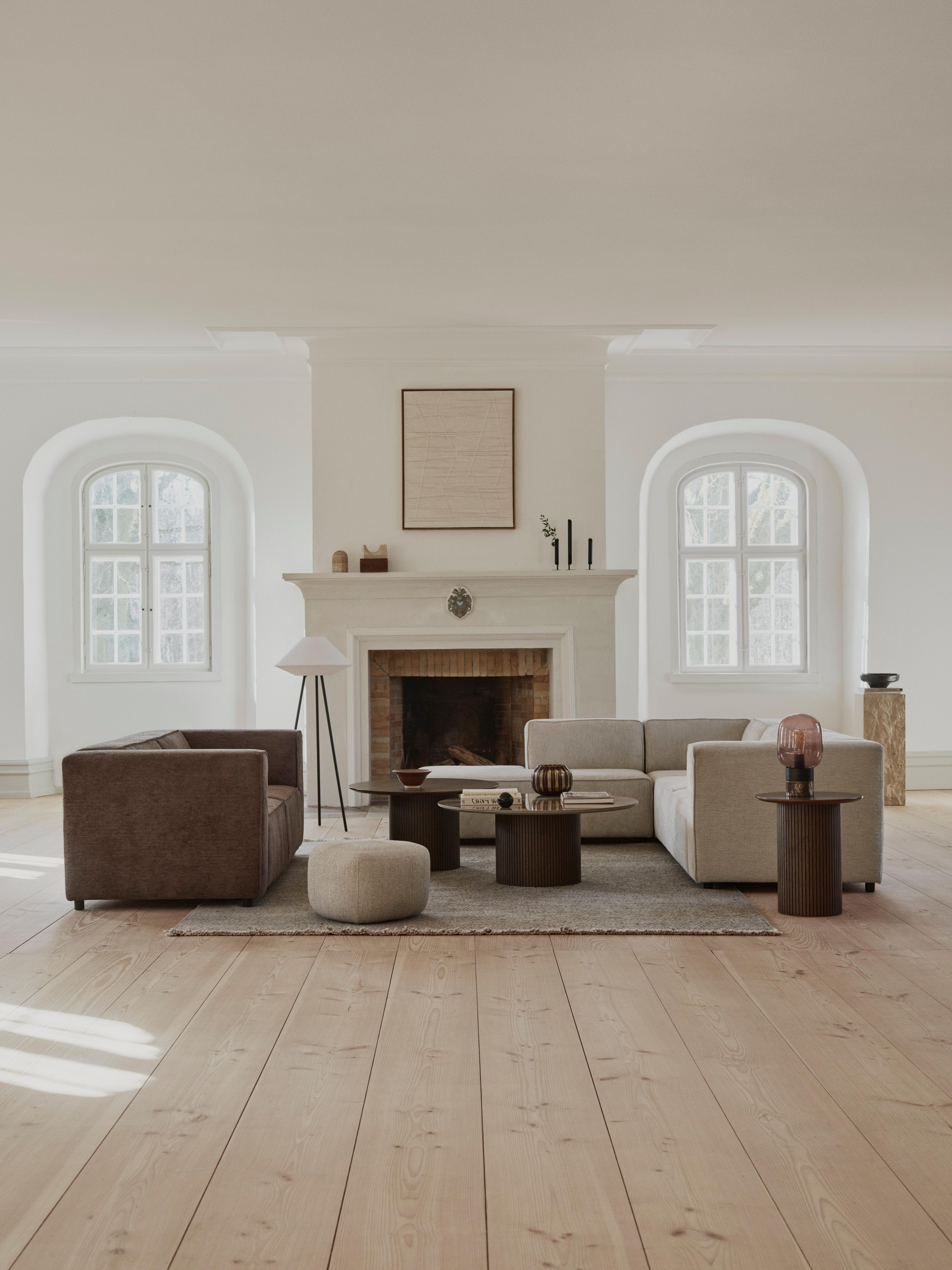 Modernes Wohnzimmer mit zwei Sofas, Couchtischen und Kamin zwischen zwei Fenstern.