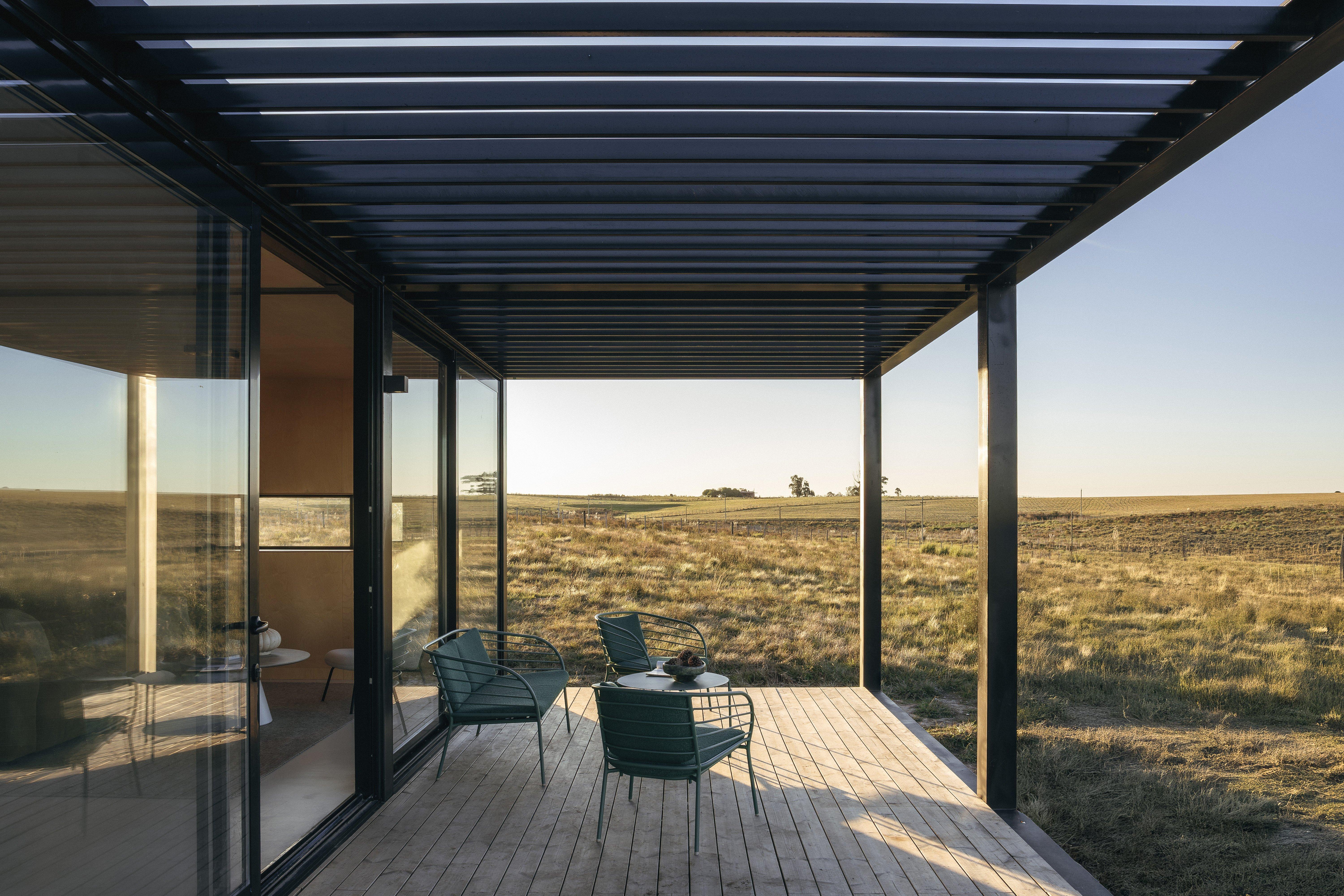 現代陽台景觀，有兩張綠色椅子和一張小圓桌，眺望遼闊草原。