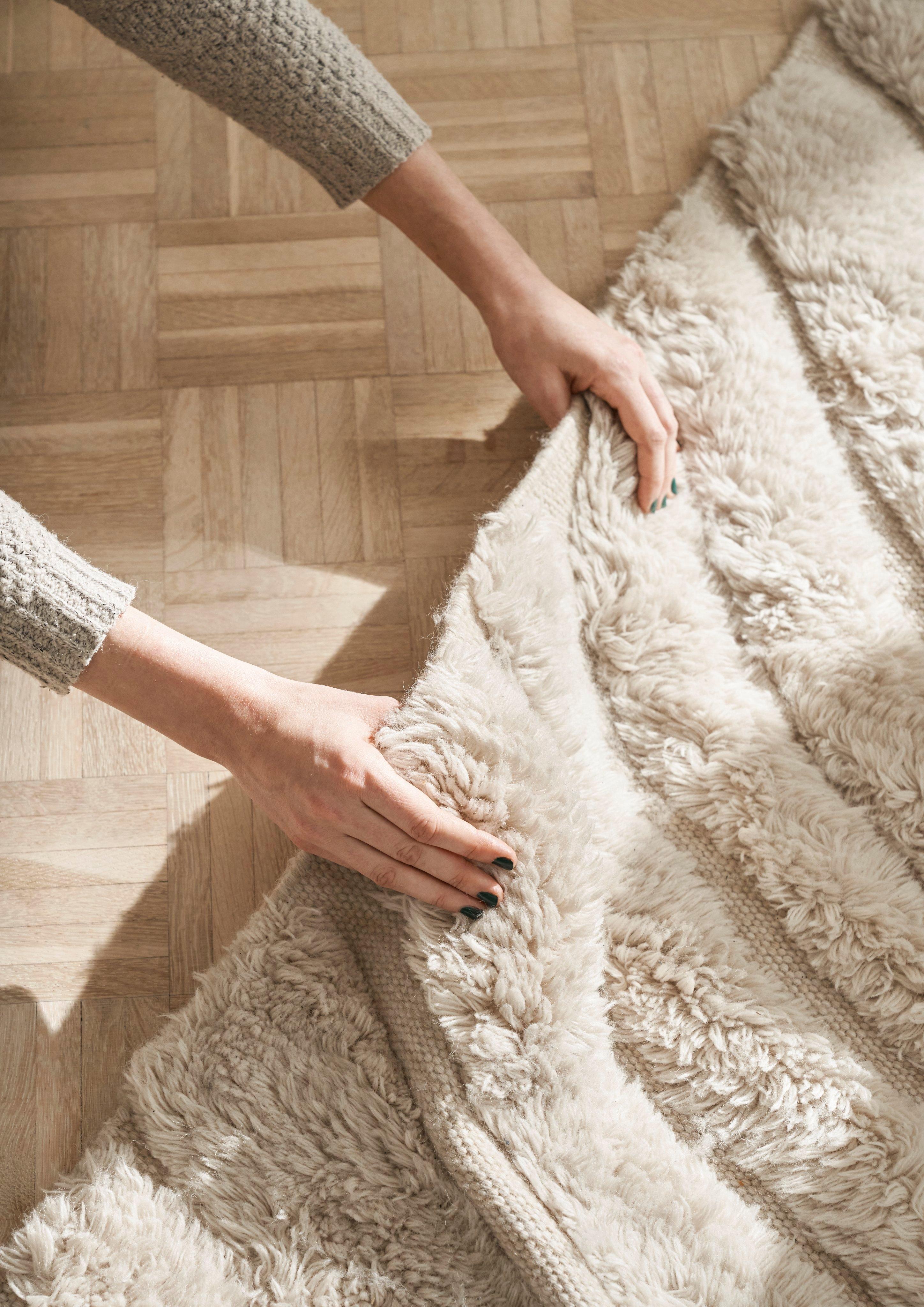 Persons hænder rører ved teksturen på Form tæppe.