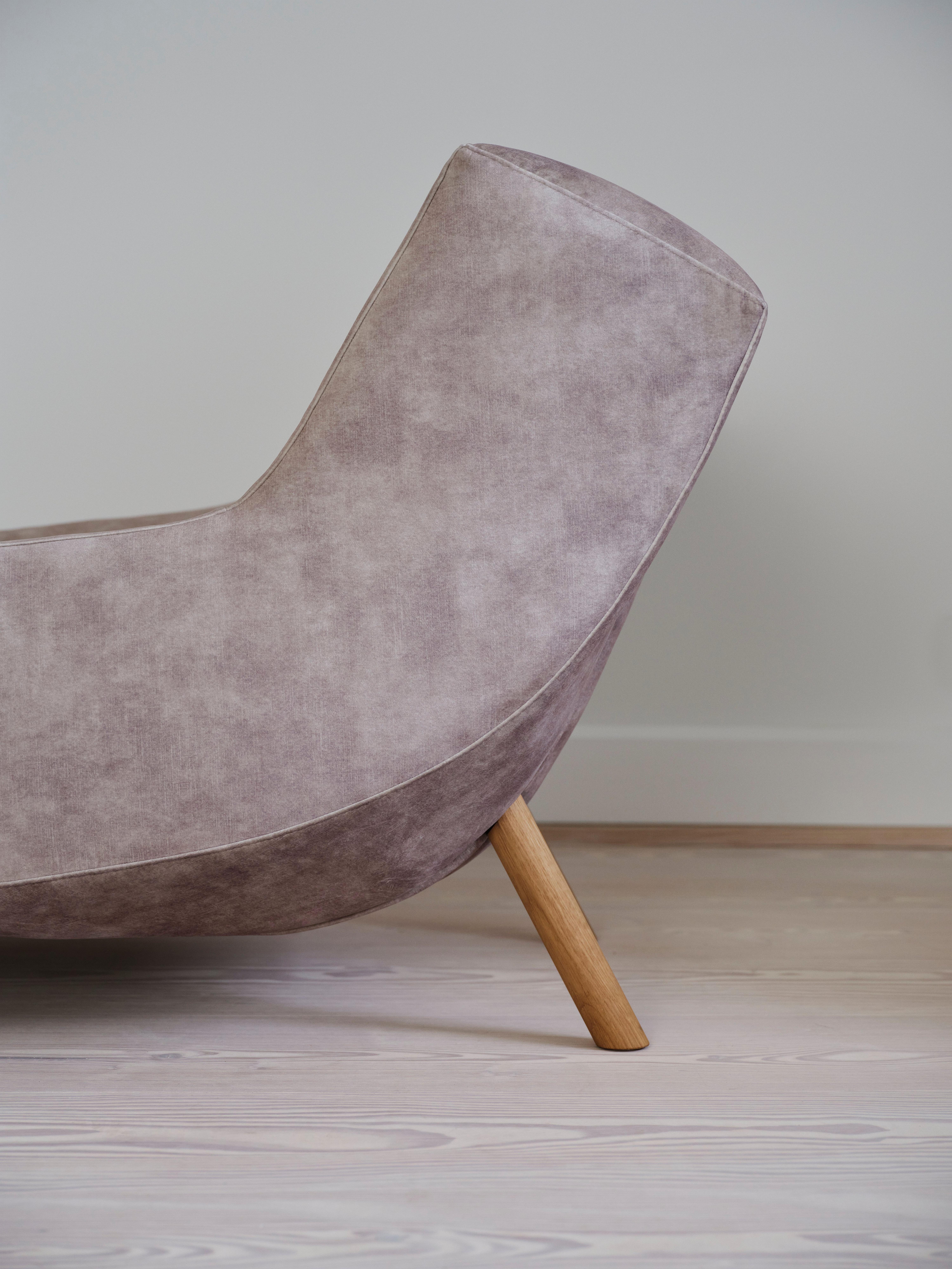 Vaaleanpunainen nojatuoli puisilla jaloilla, sivukuva.
