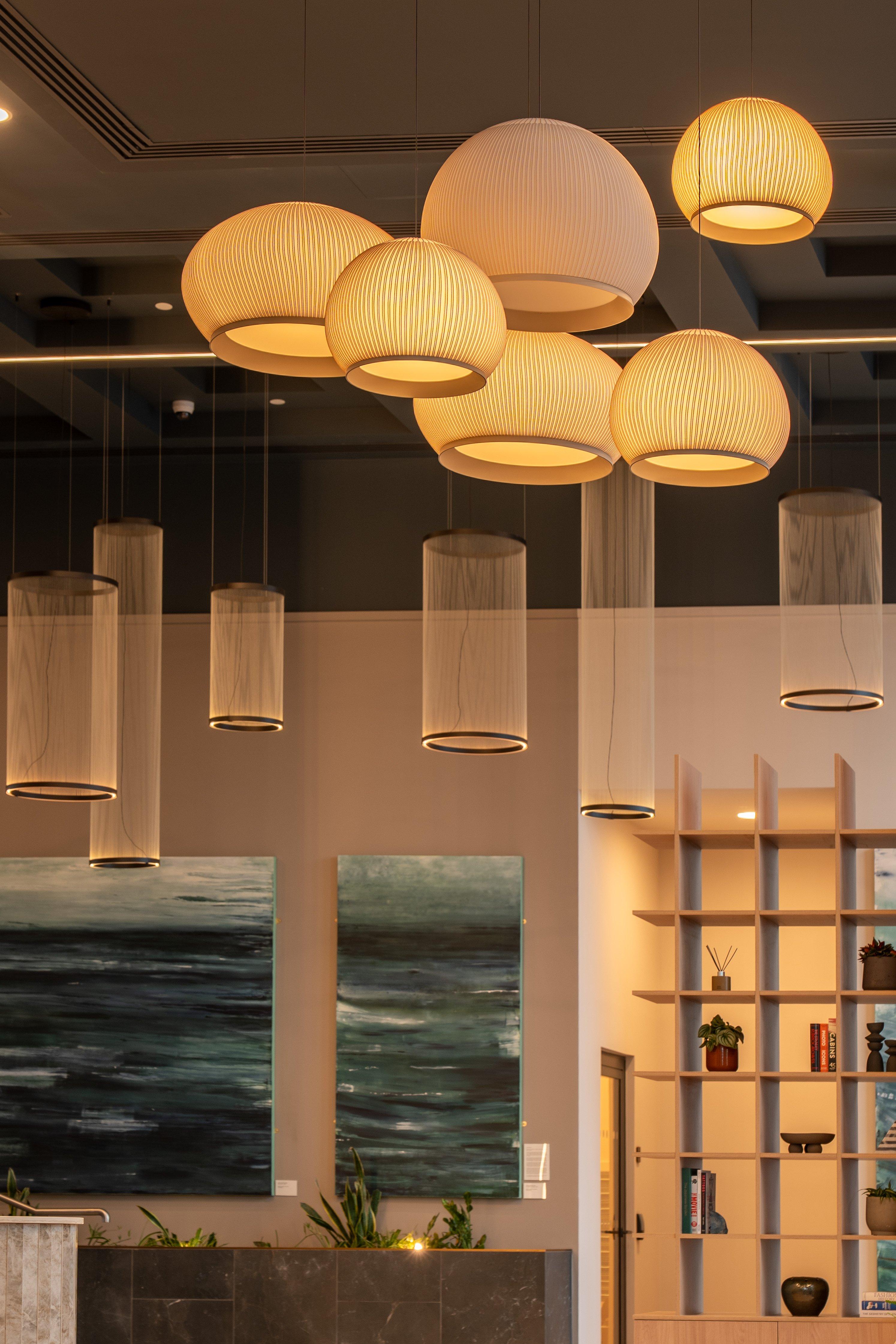 Conjunto de lámparas colgantes esféricas y cilíndricas encendidas en interior moderno.