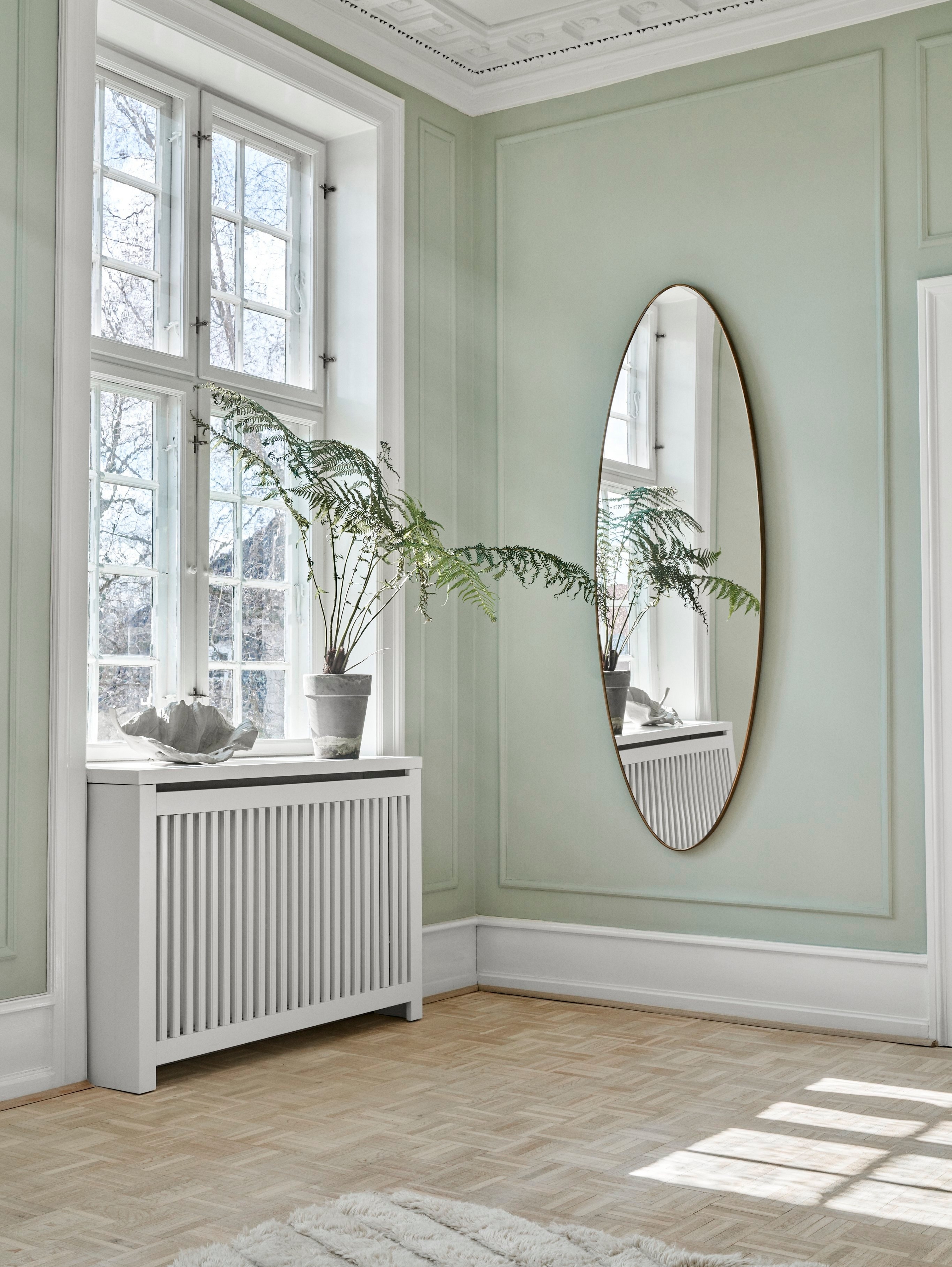 Lyst hjørne med spejl, plante og Magnolia skulptur.