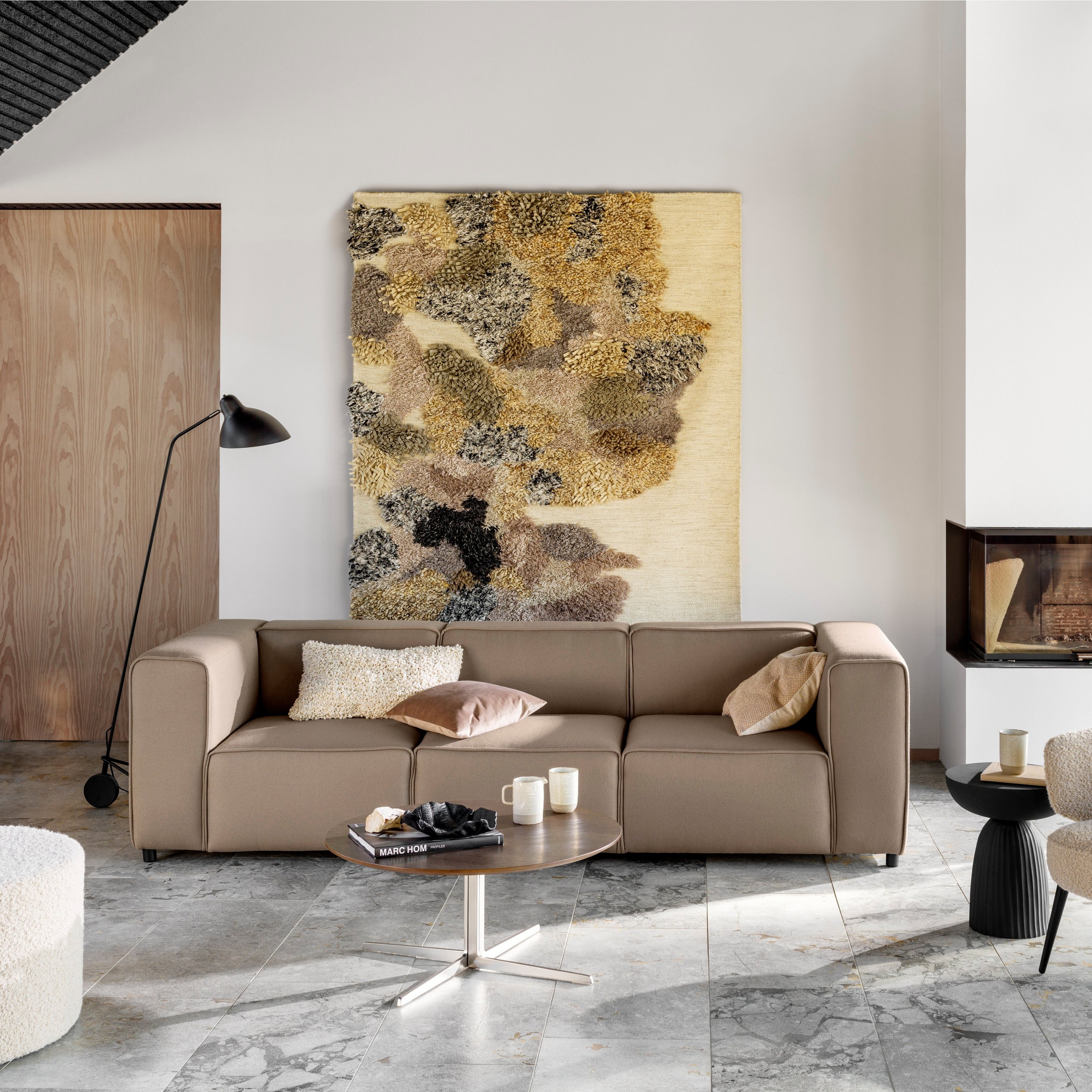 Stue med sofa, stol, kunst, peis, gulvlampe og marmorgulv.