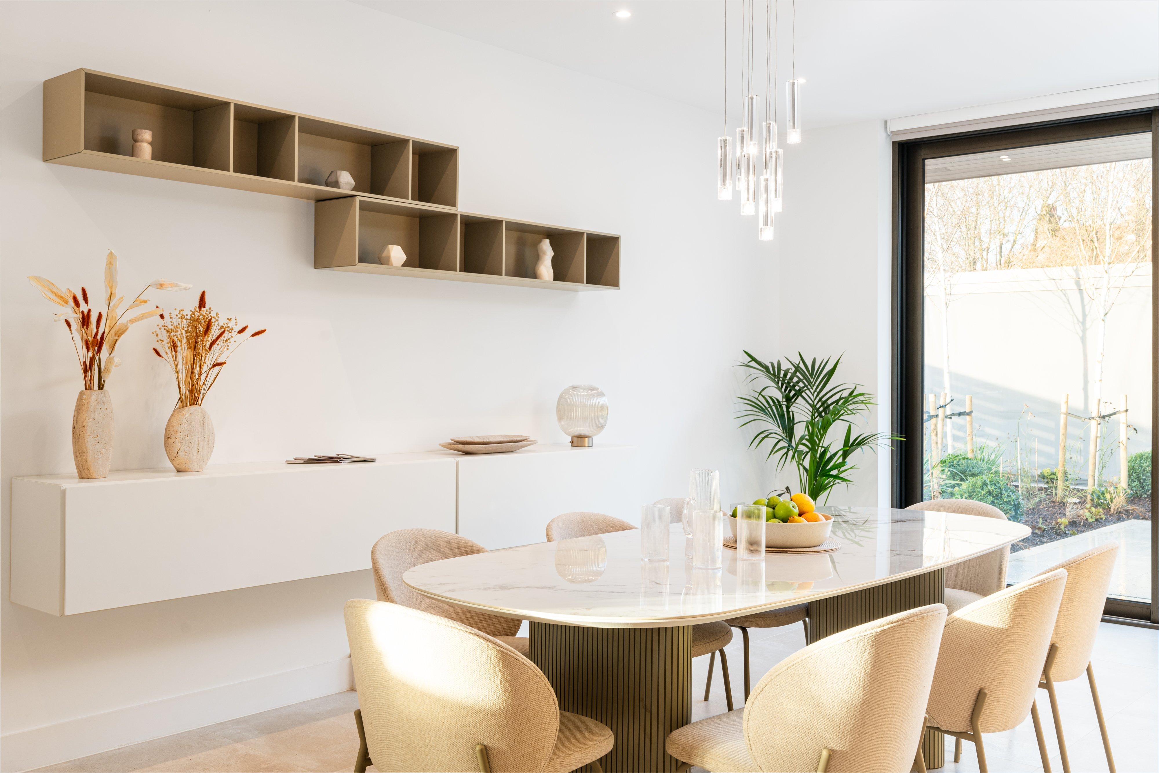 Modern dining table with upholstered chairs, hanging pendant lights and fruit bowl centrepiece.
