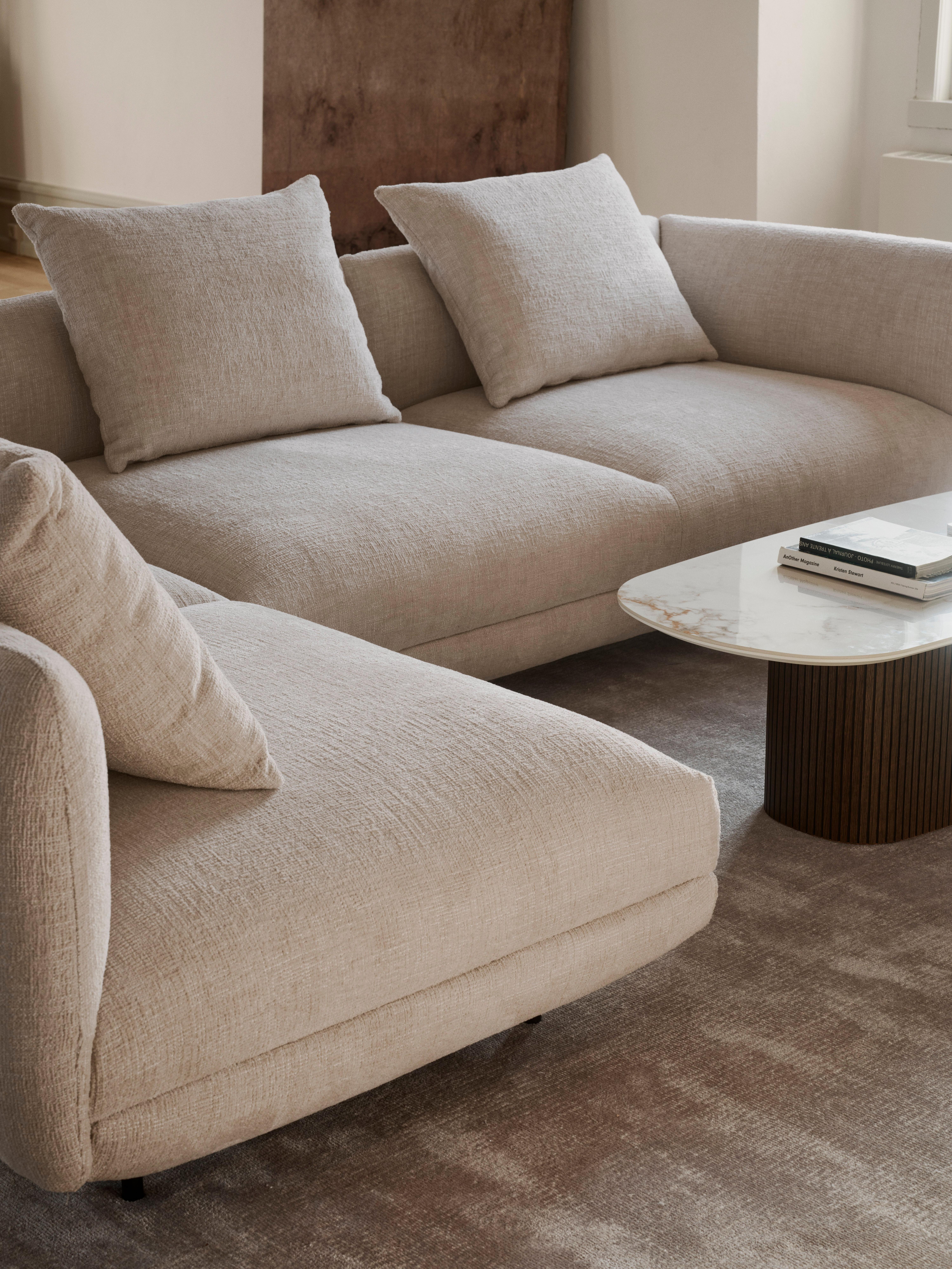 Lysebeige stofsofa med to store puder ved et sofabord med marmorlook.