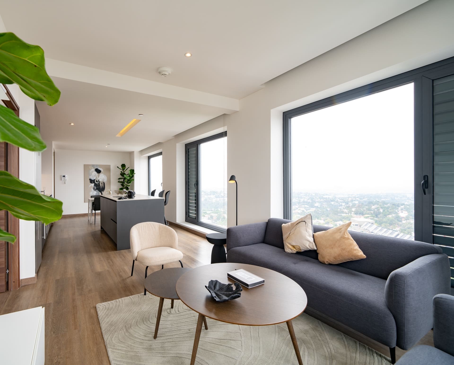 Spacious modern living room with large windows, city view, and open-plan interior design.