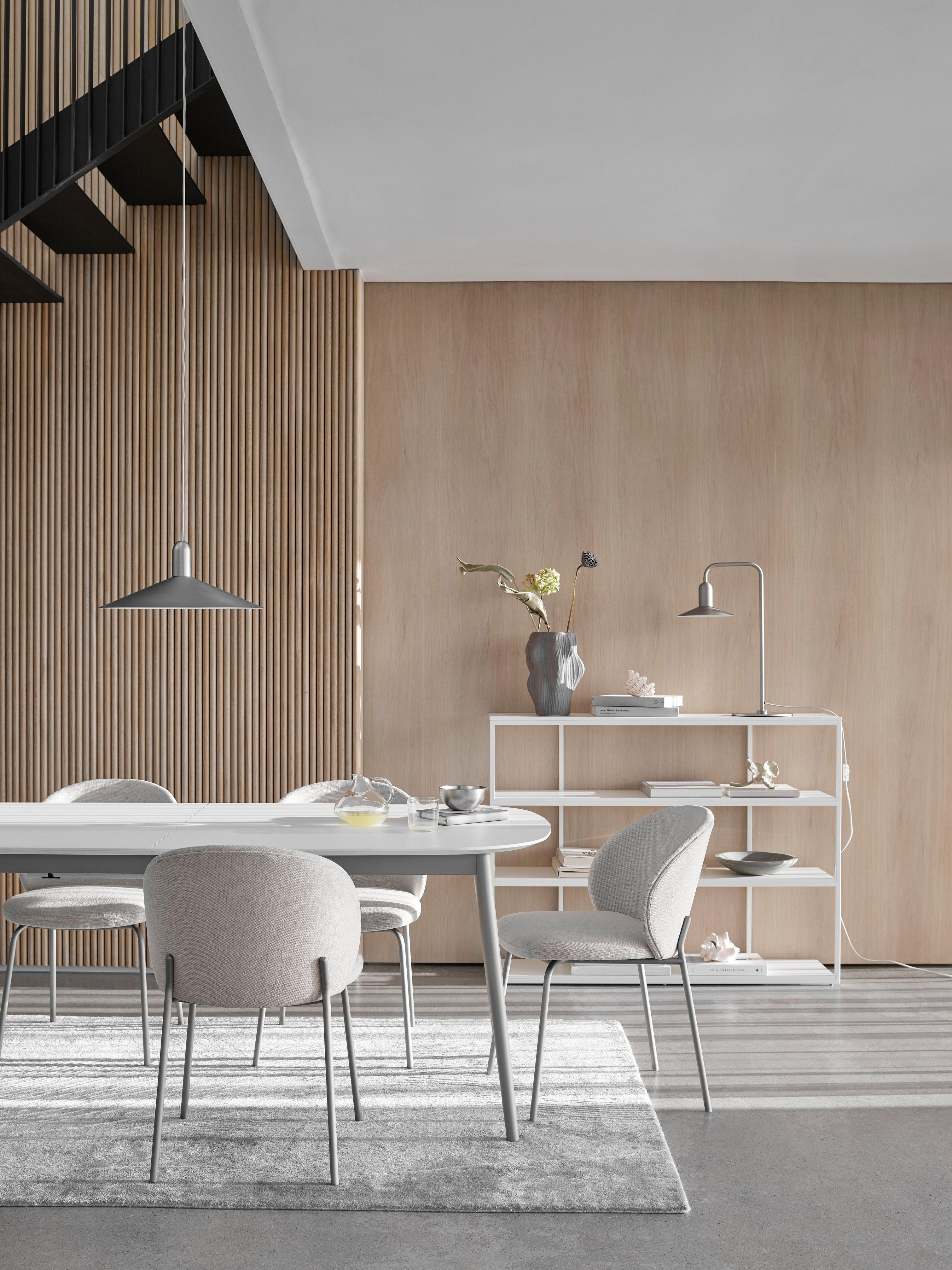 Modern dining room with light chairs, table, pendant light, and shelving against wooden slatted wall.