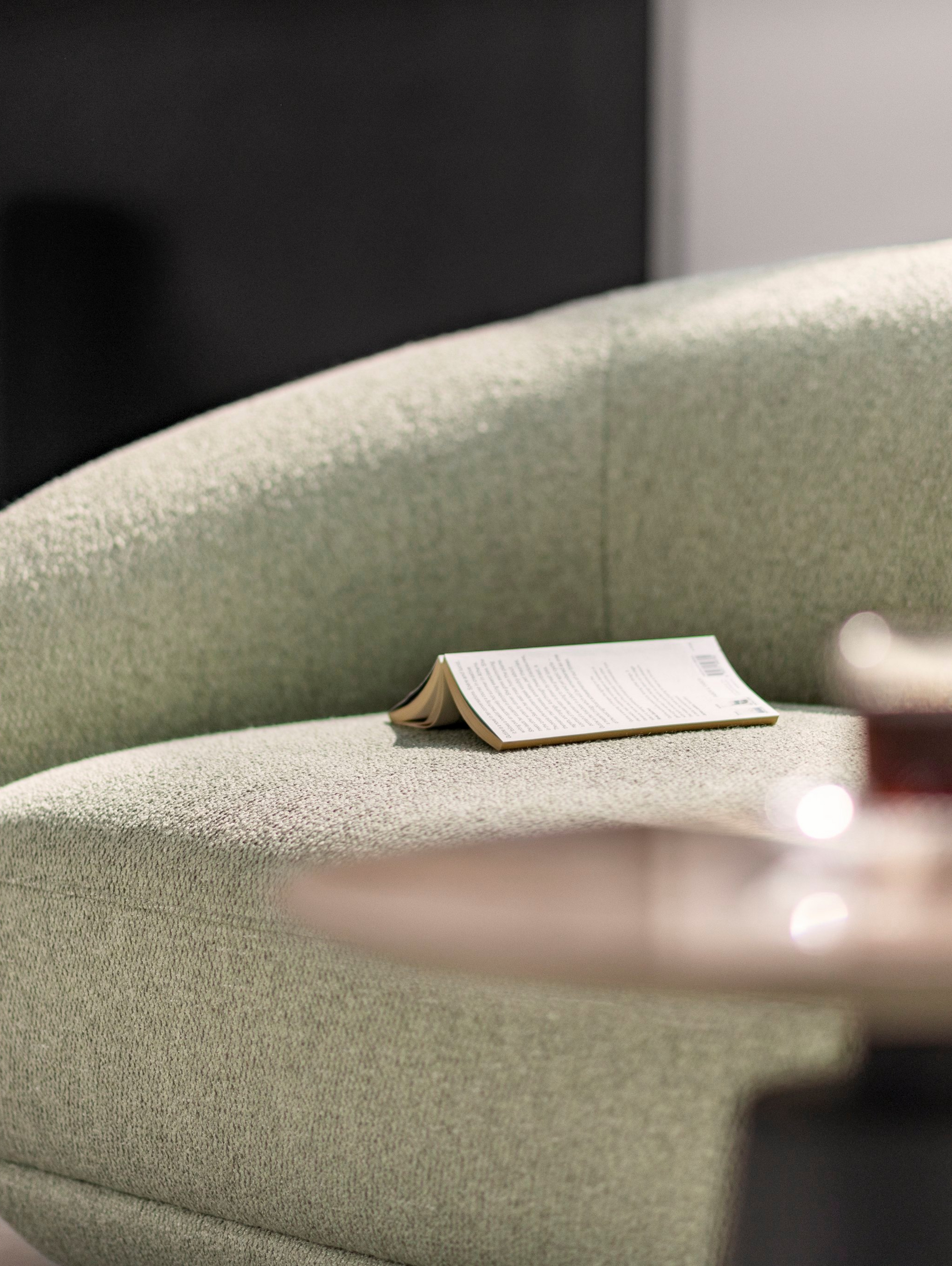 Book resting on the Bolzano chaise longue in light green Lazio fabric.