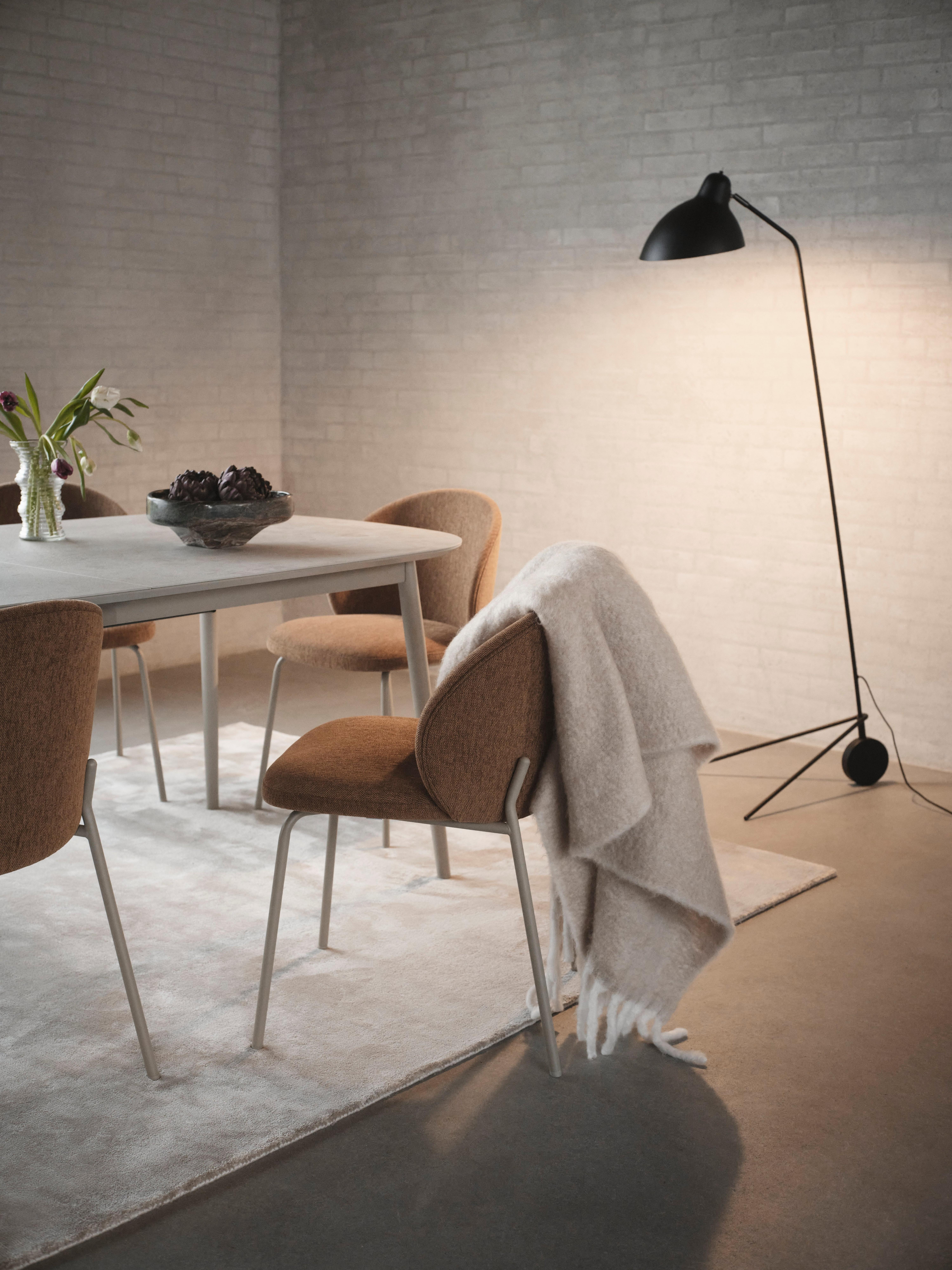 Kingston dining table in ash ceramic with Princeton chairs in mustard fabric, black Demand floor lamp, and stone grey Simple rug.