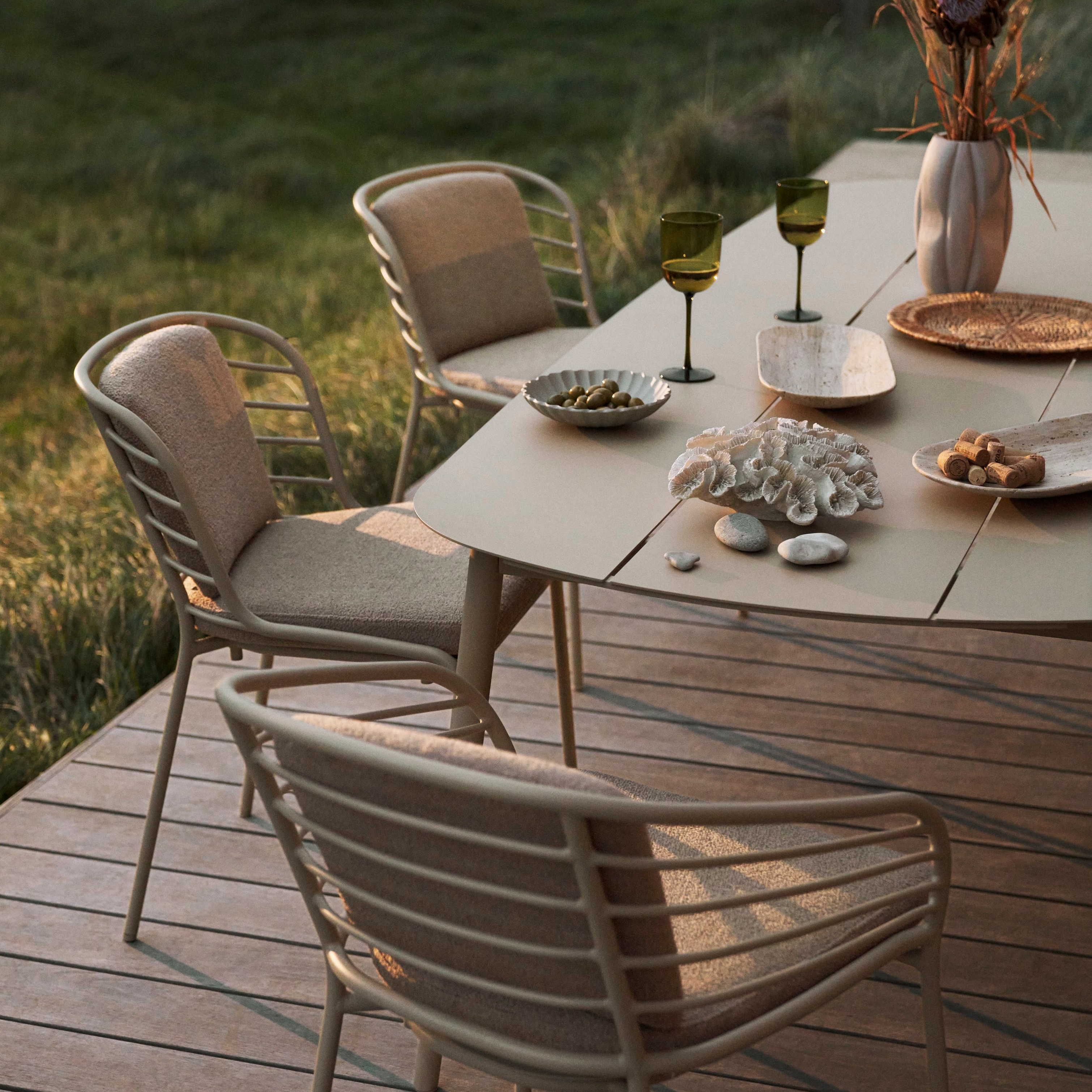 Spisemiljø med Cancún bord og spisebordsstole i mat askegrå vist udenfor i solnedgangen.