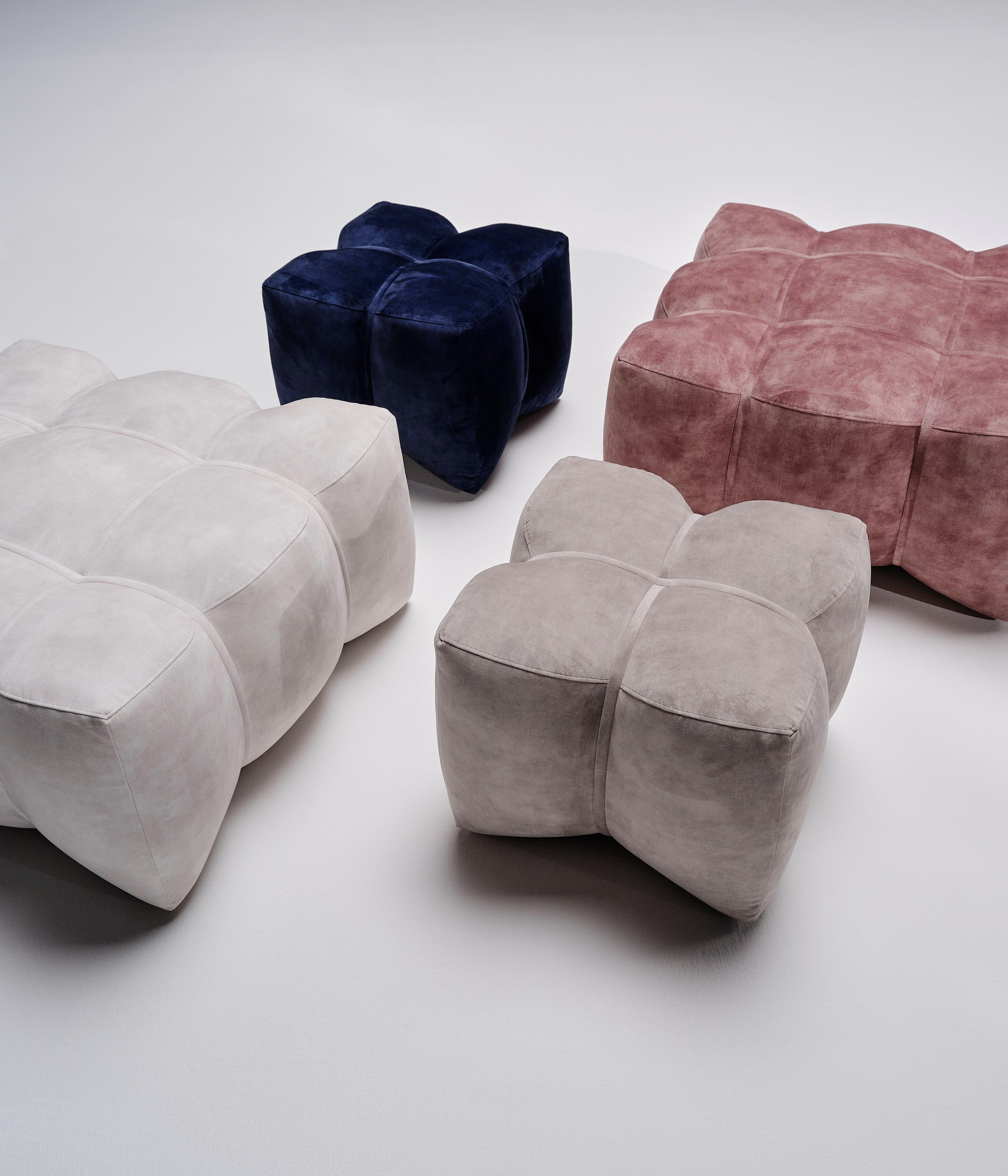 Nelikulmaisia, pehmeitä jakkaroita eri väreissä: valkoinen, harmaa, sininen ja vaaleanpunainen.