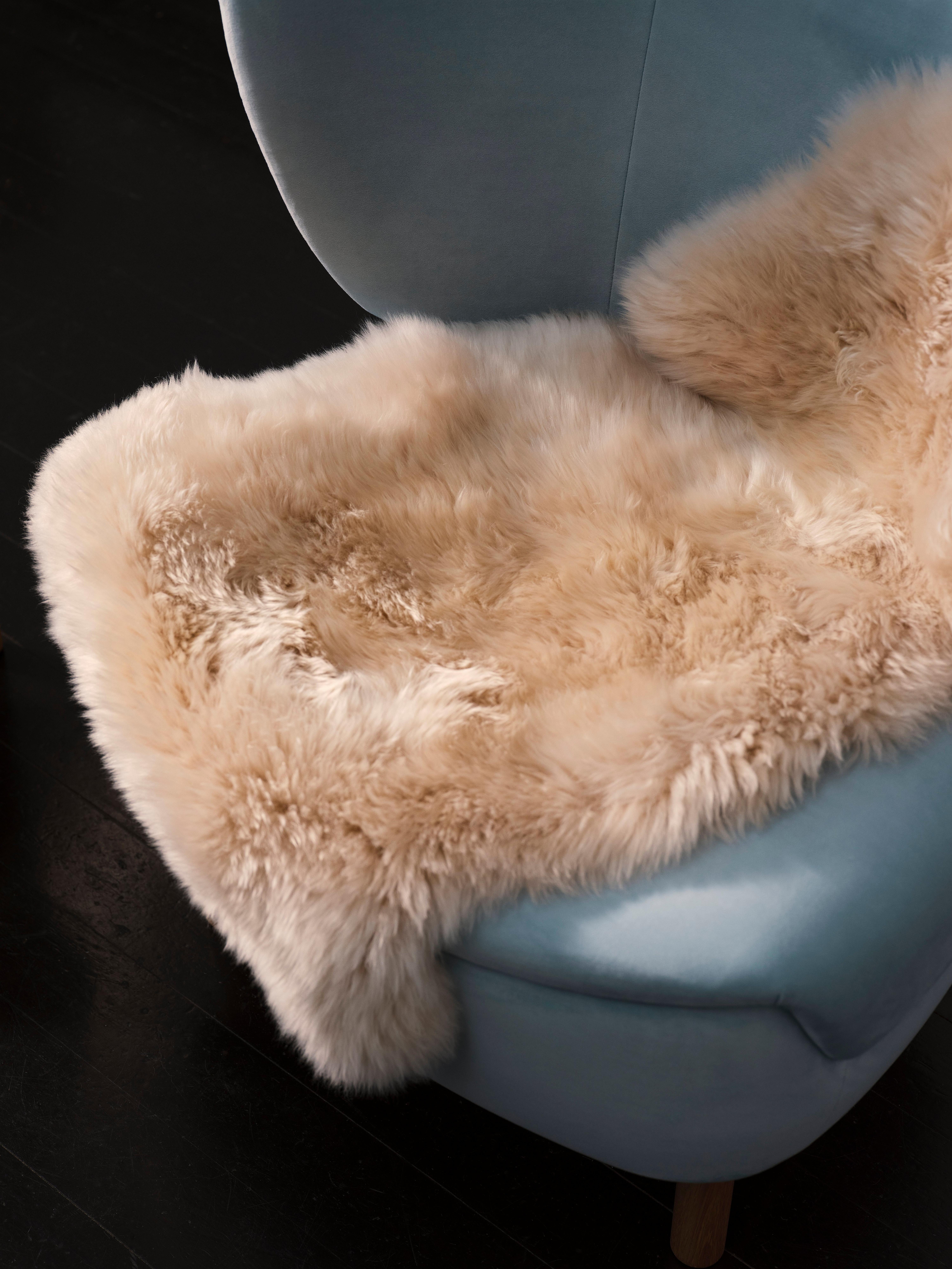 Ullteppe lagt over en blå stol med mørkt gulv.