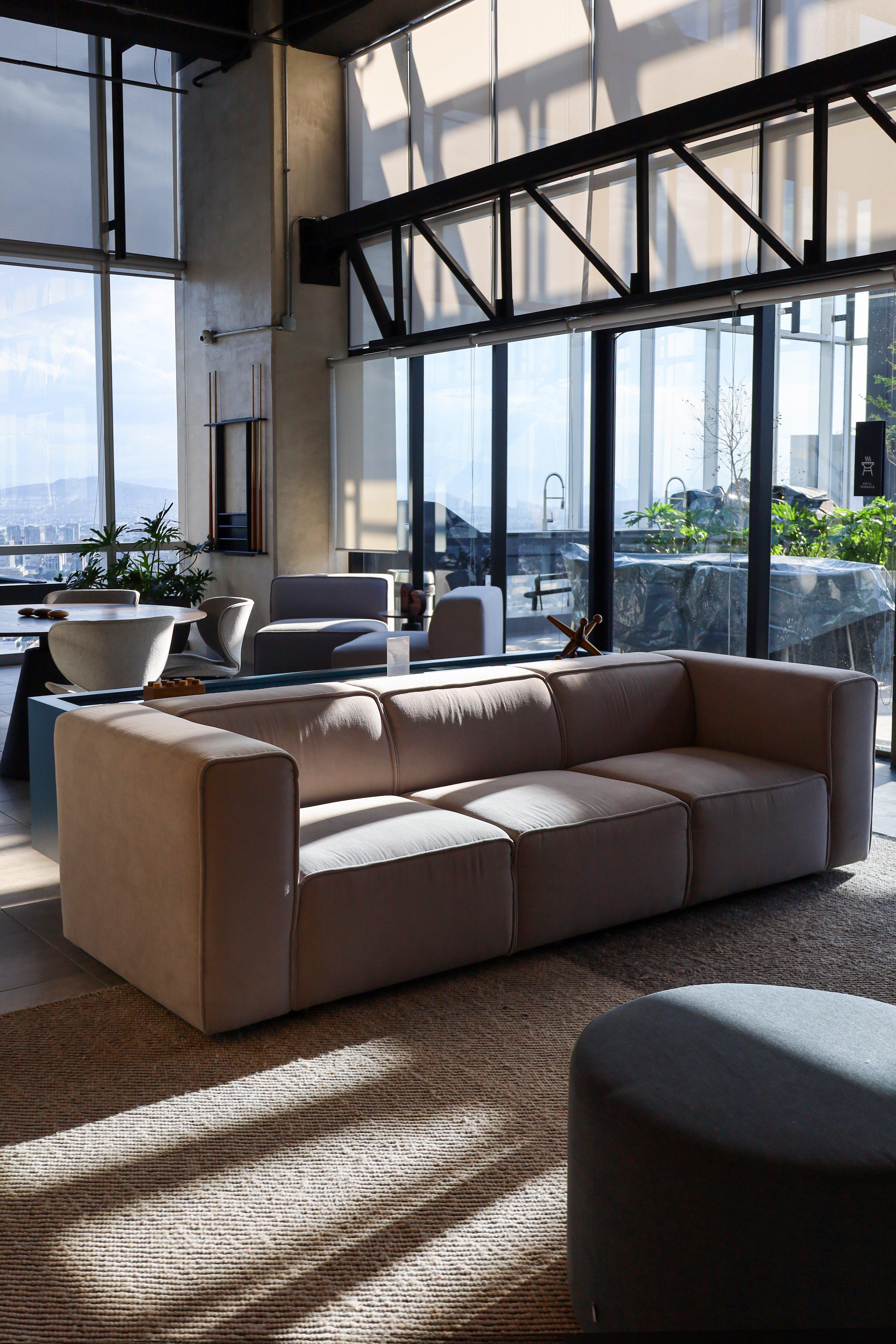 Modern living room with beige sofa, round table, and large windows.