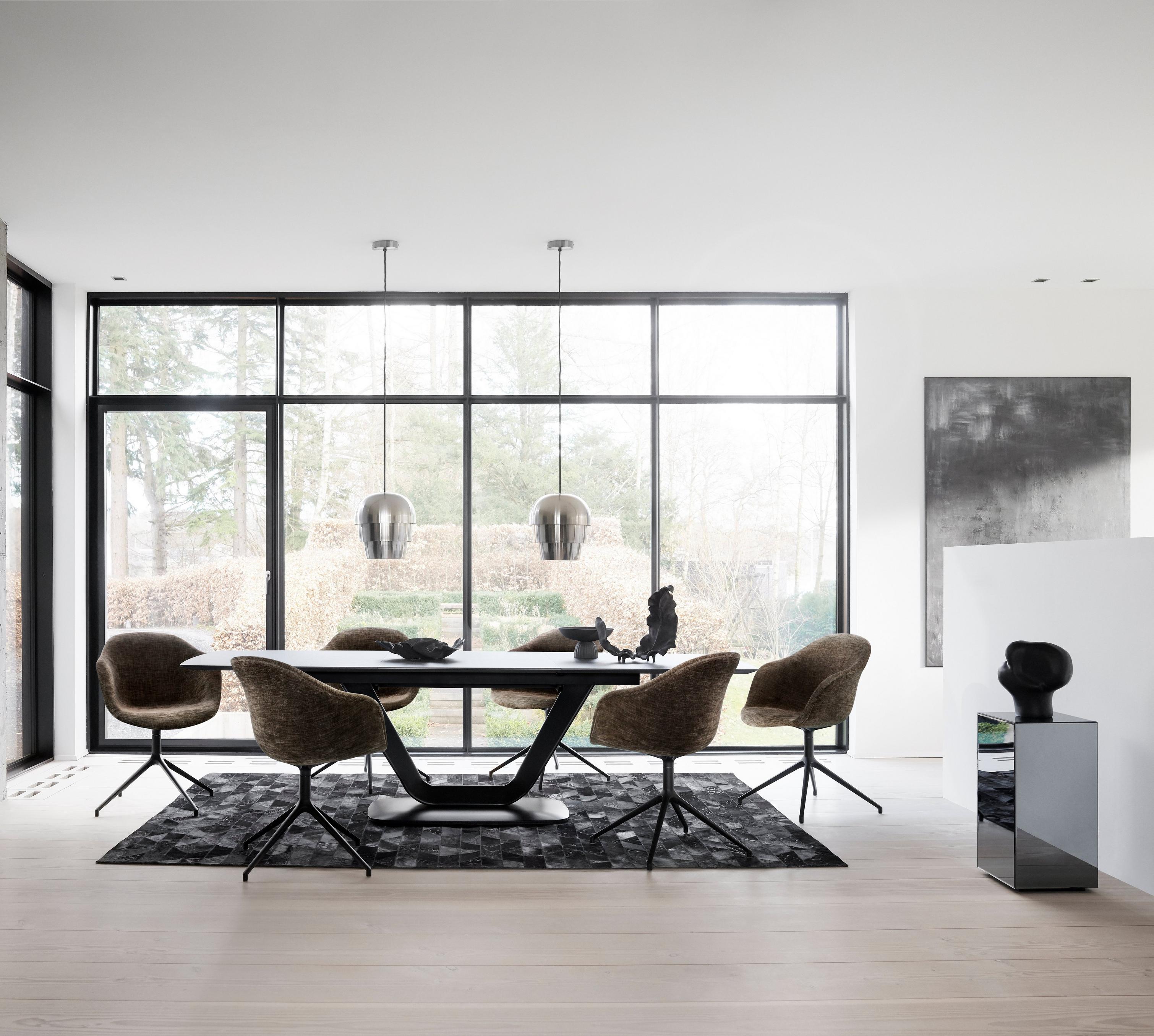 Modern dining room with textured chairs, a sleek table, art pieces, and floor-to-ceiling windows.