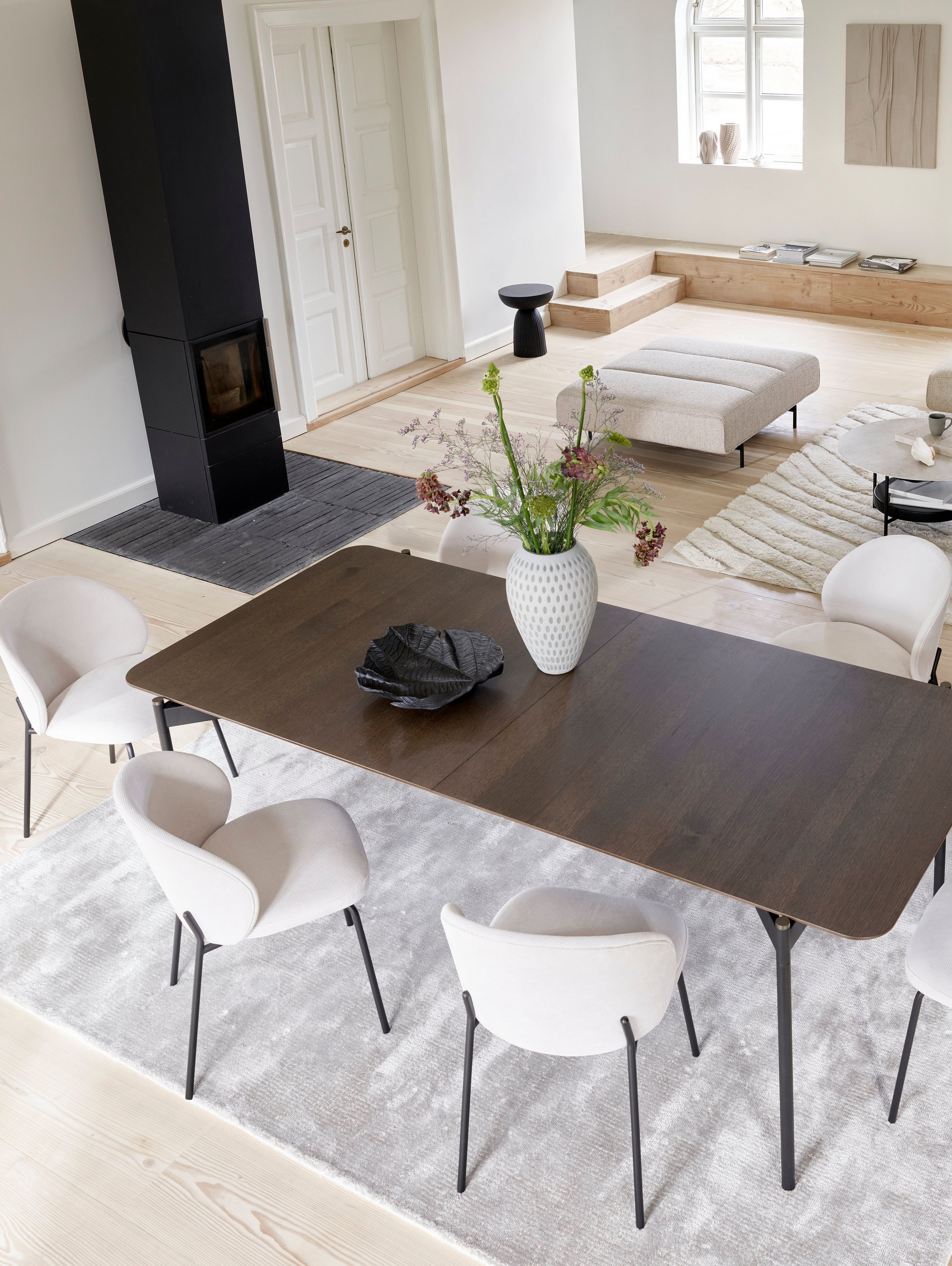 Amsterdam Ecksofa mit Lounging-Modul und Hocker aus beigefarbenem Lazio Stoff mit Augusta Tisch in einem schönen großen Wohnzimmer.