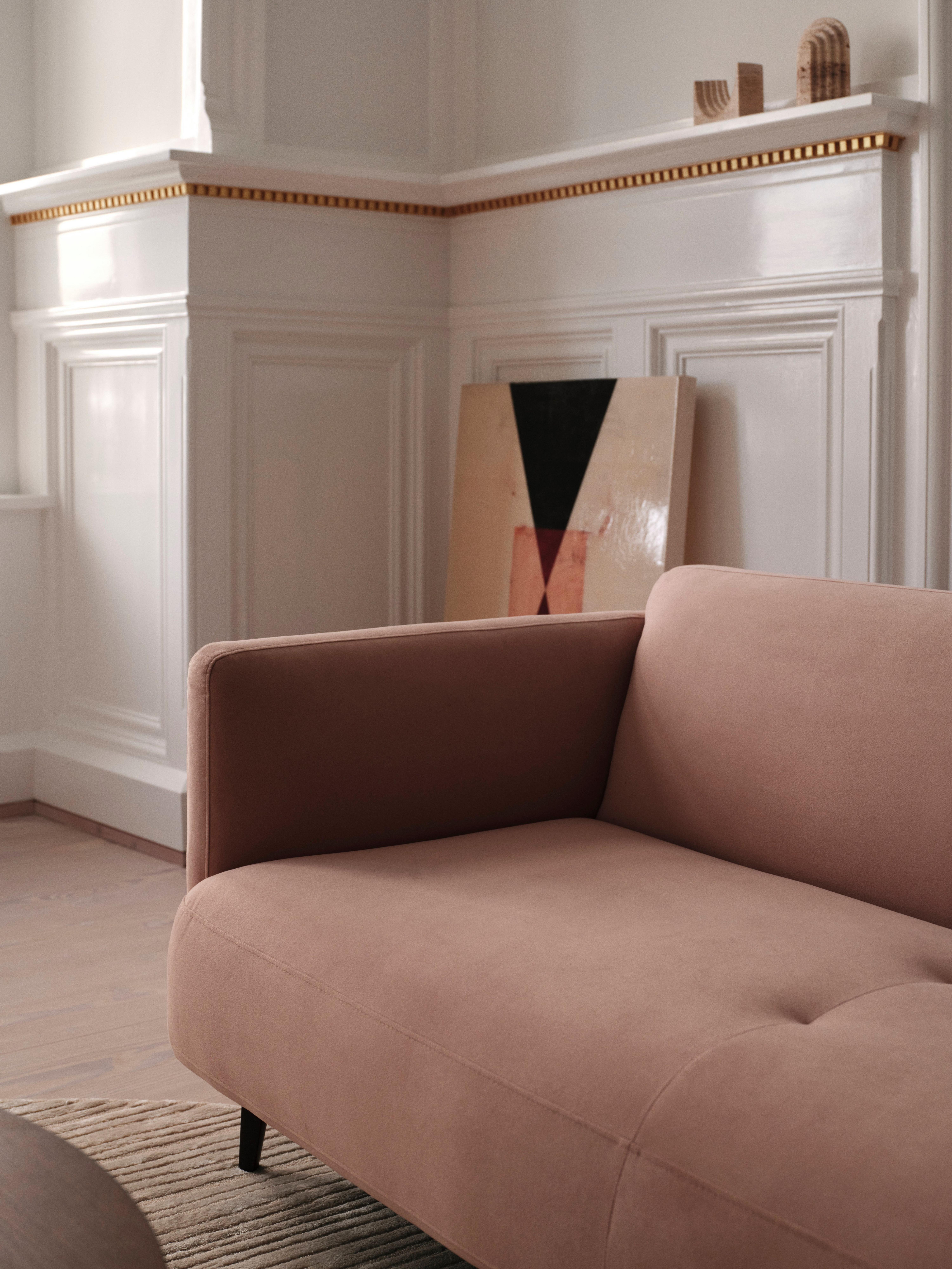 Braunes Sofa in elegantem Raum mit weißen Vertäfelungen und geometrischem Kunstwerk.