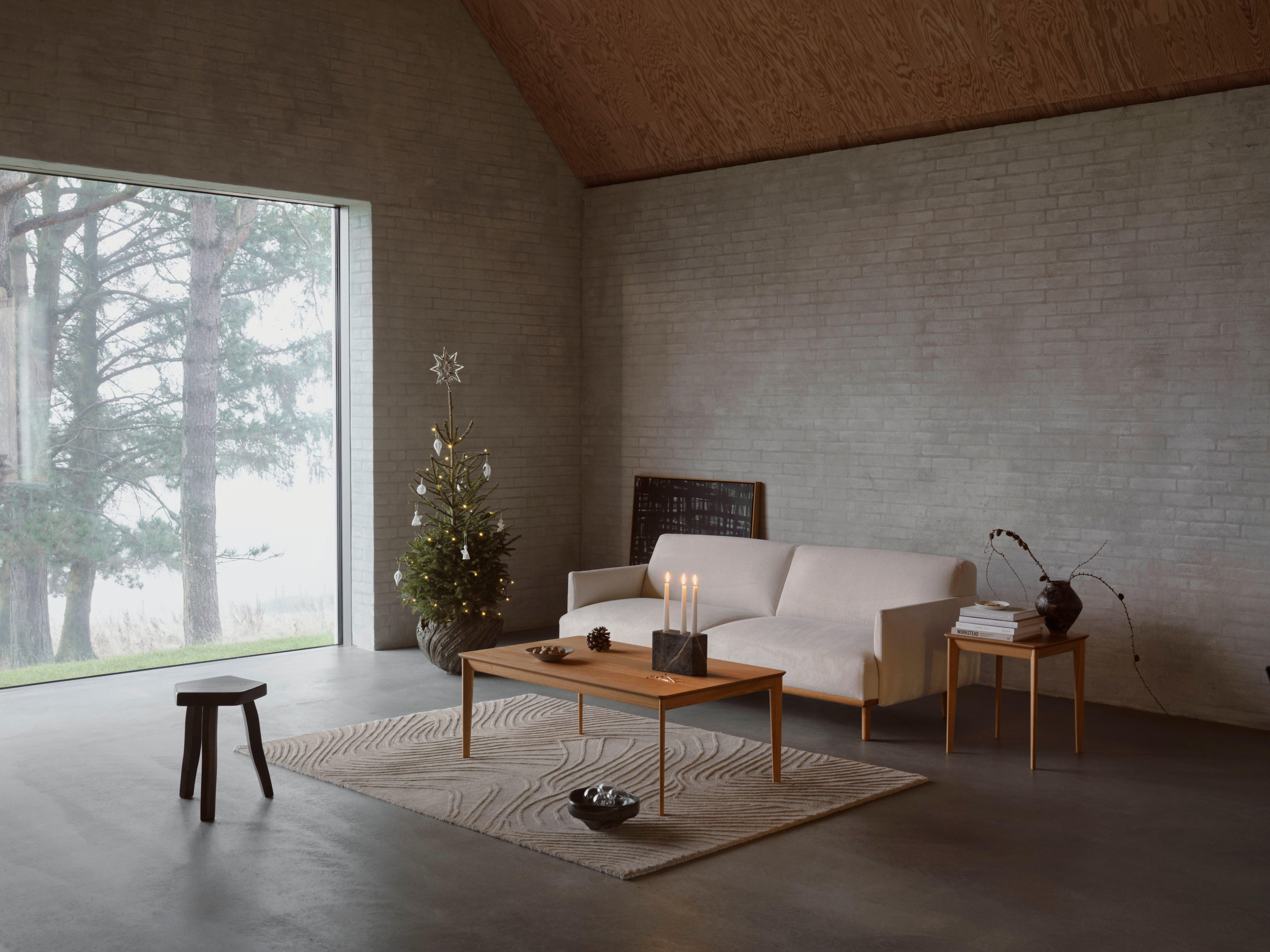 Aarhus coffee table and side table in natural oak veneer with Aarhus 3-seater sofa in white Copenhagen fabric, Ridge rug, Fracture Candlestick, and Curve bowl in forest green.