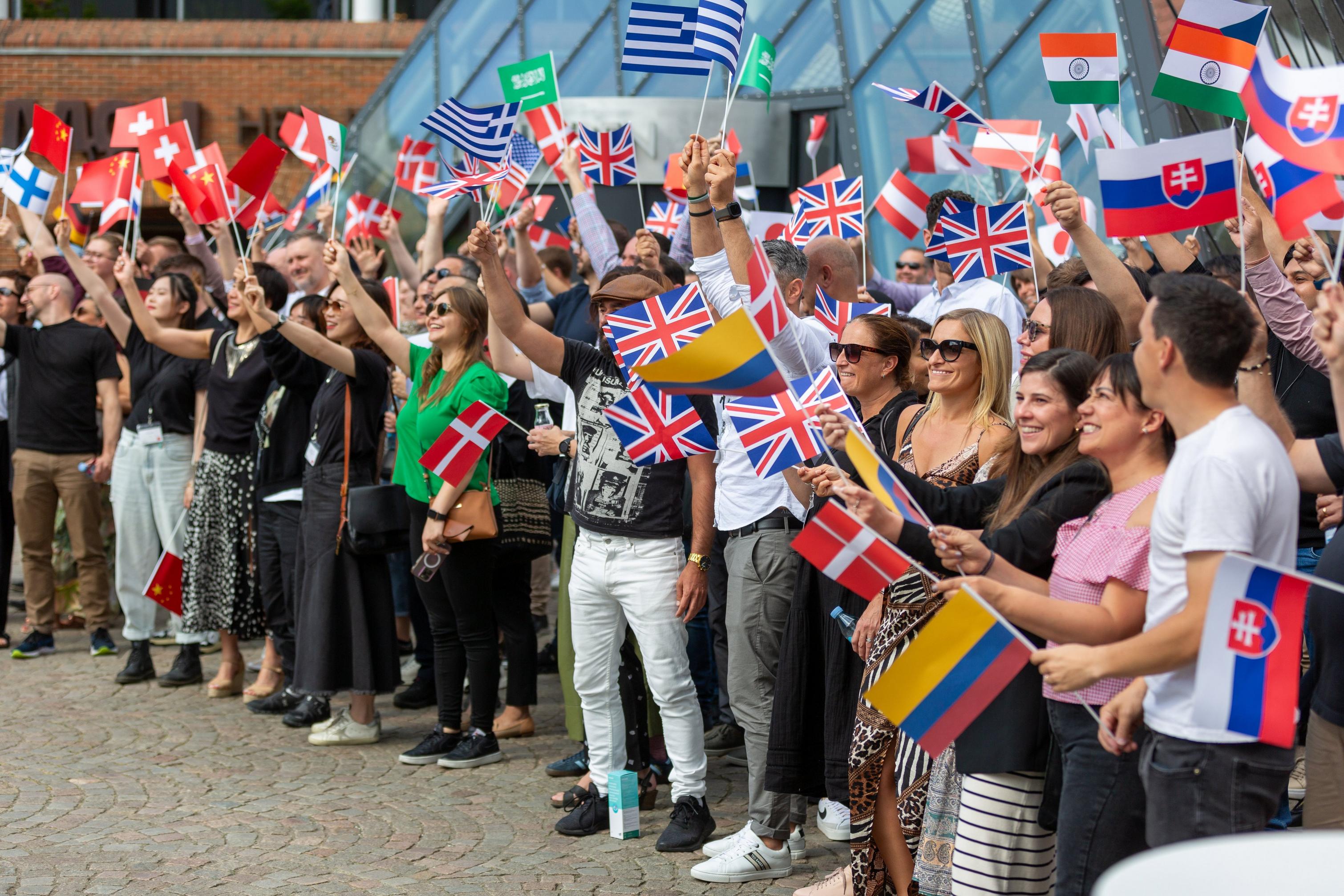 Un grupo de empleados de BoConcept animando con varias banderas nacionales en la mano.