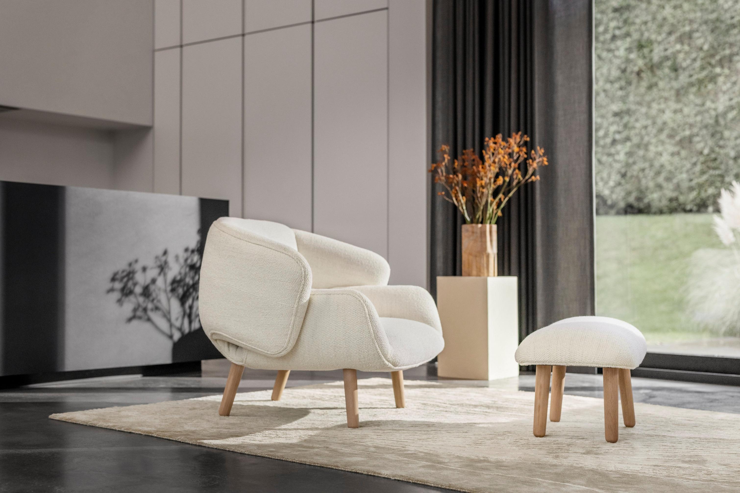 Sala de estar luminosa com a cadeira Fusion em tecido Lazio branco e o apoio de pés a condizer.