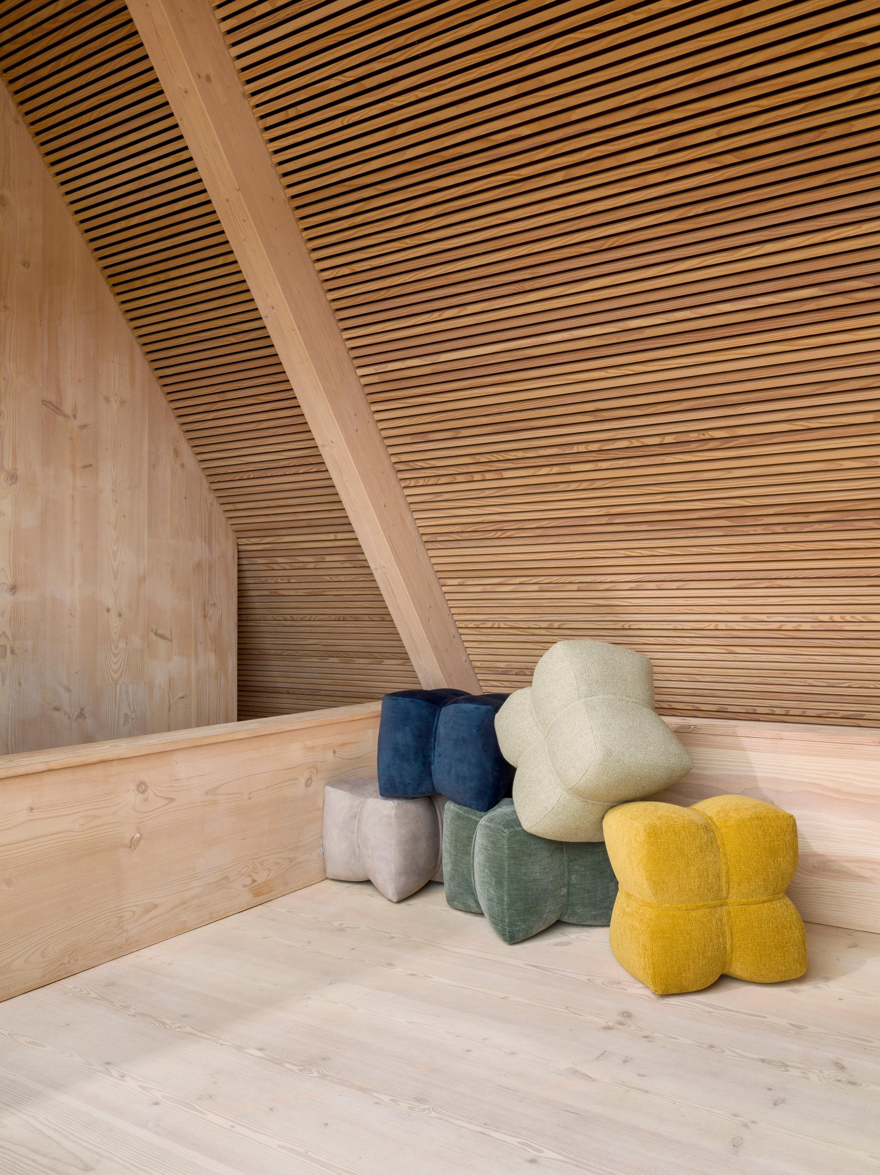 Several Nawabari pouffes upholstered in Ravello, Napoli, Tomelilla and Lazio fabrics sit in the corner of a wooden room.