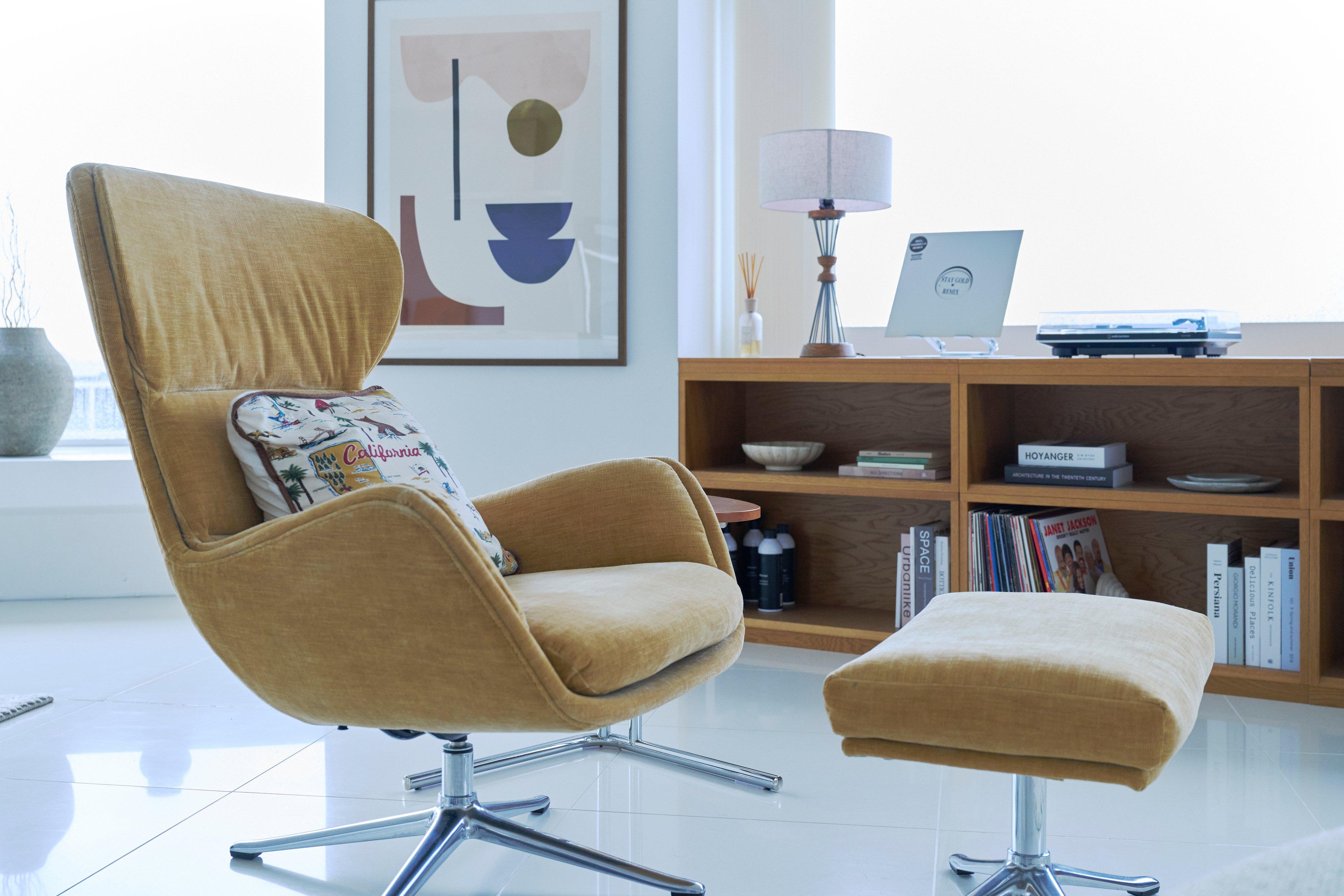 Upholstered swivel armchair with matching footstool in a living room.