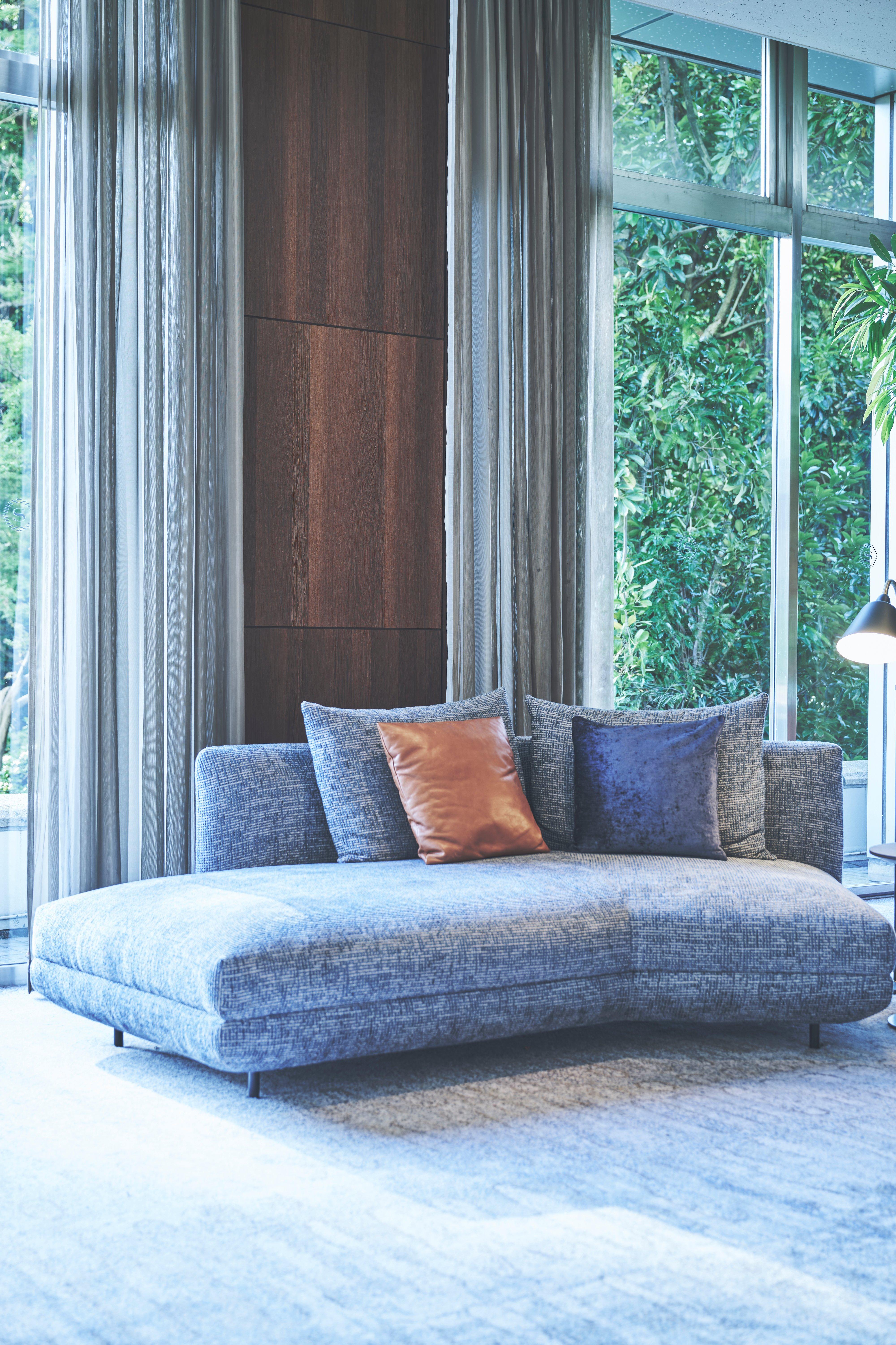 Grey upholstered chaise sofa with mixed cushions in a modern living room.